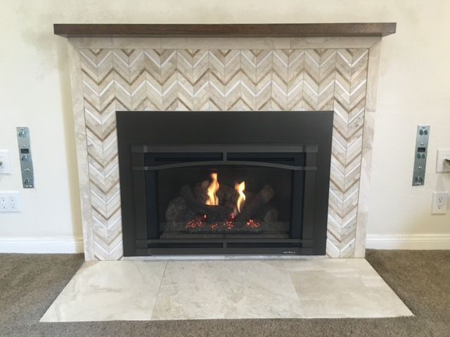 A fireplace with a chevron pattern on the wall.