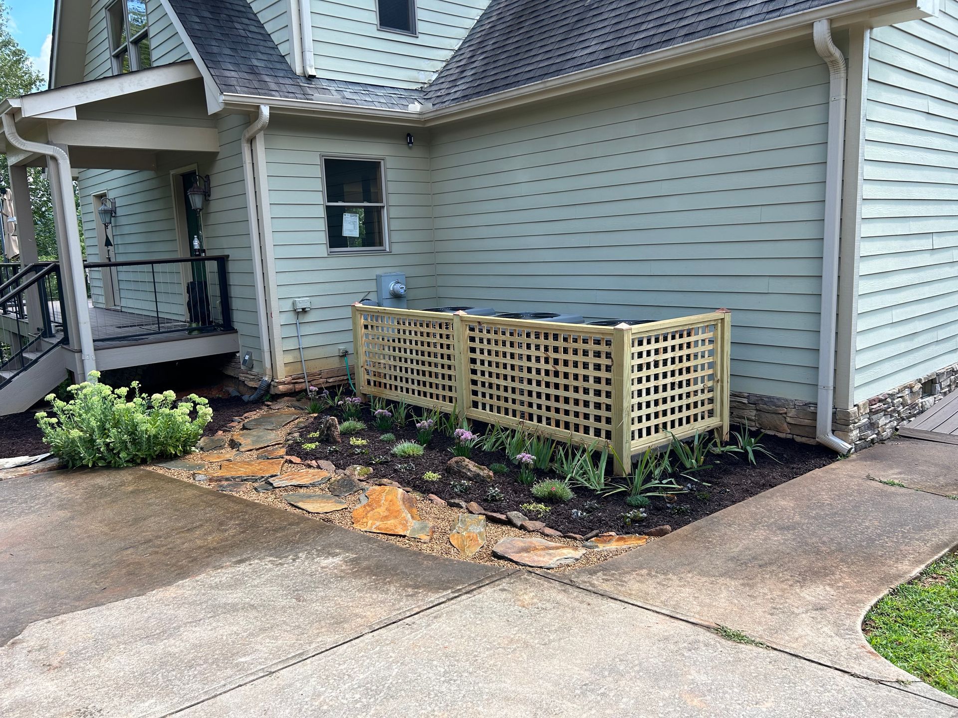 House exterior with a small wooden lattice planter box and newly mulched garden bed by the driveway