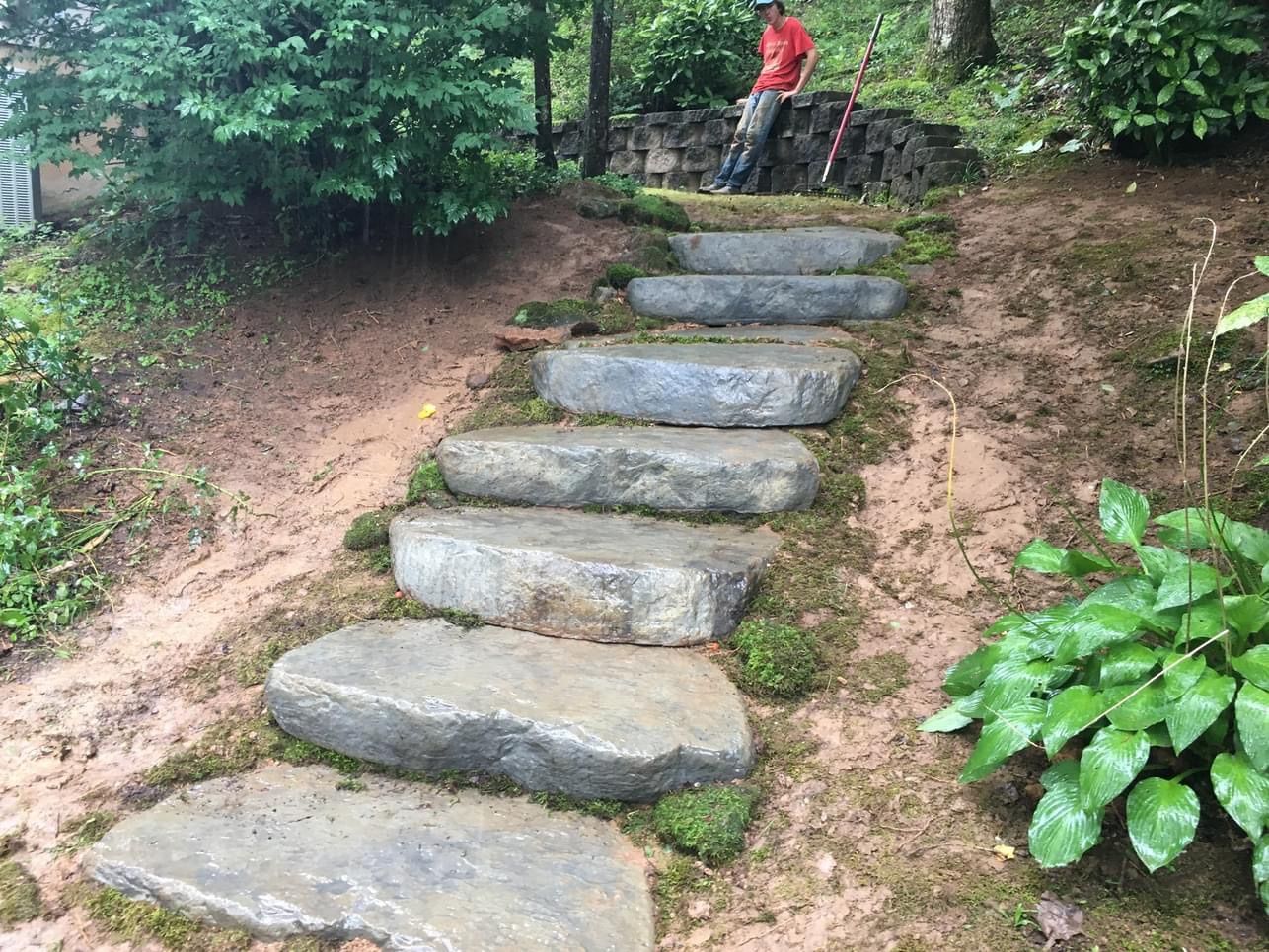 Stone steps up a wooded hillside, with a person in a red shirt standing at the top.