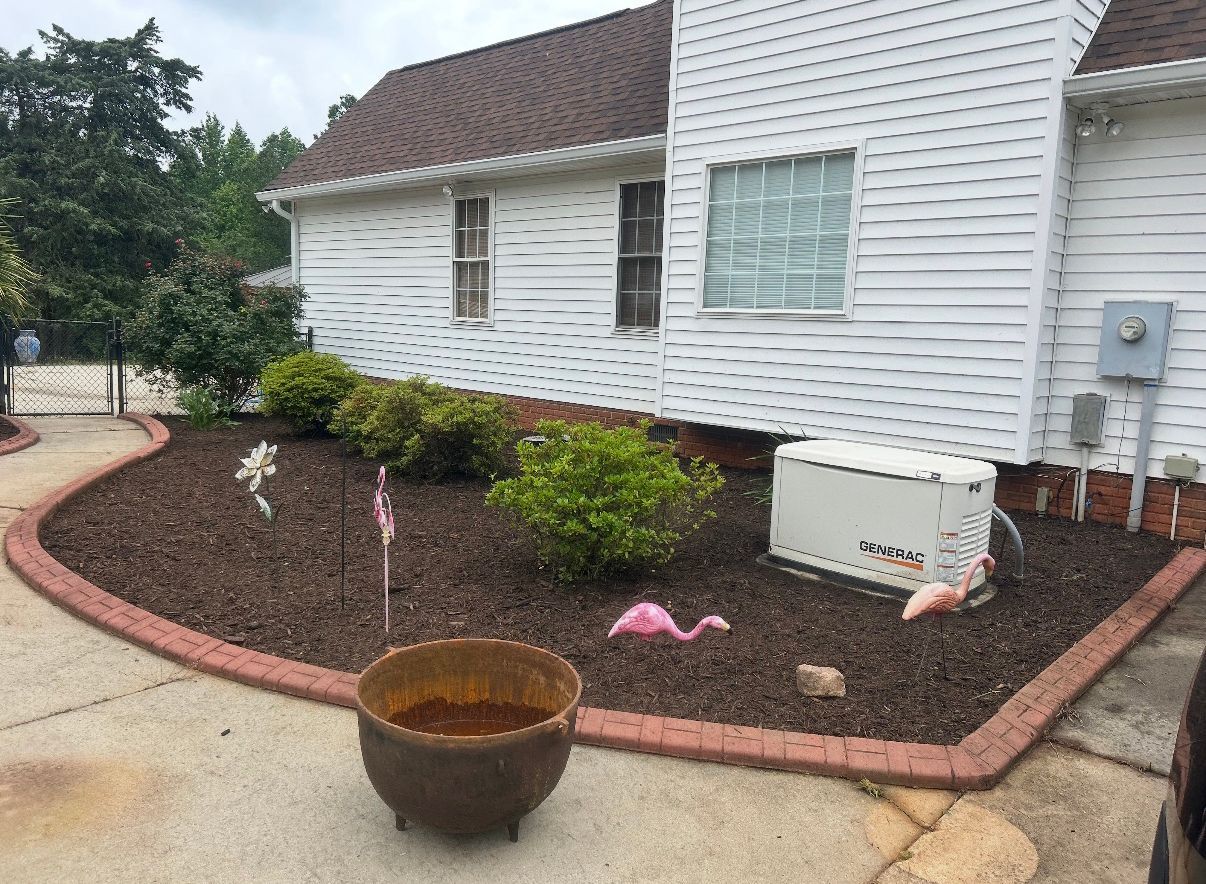 White house with a curved mulched flower bed, small shrubs, and a planter on a concrete walkway