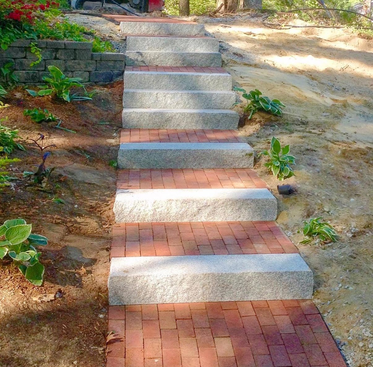 Brick and stone garden steps ascending a dirt slope with small plants on either side
