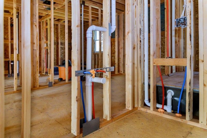 A room in a house under construction with pipes coming out of the wall.