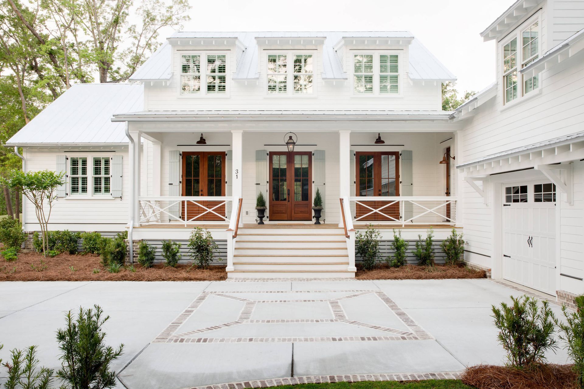 White two-story house with front porch, stairs, double garage, and landscaped driveway