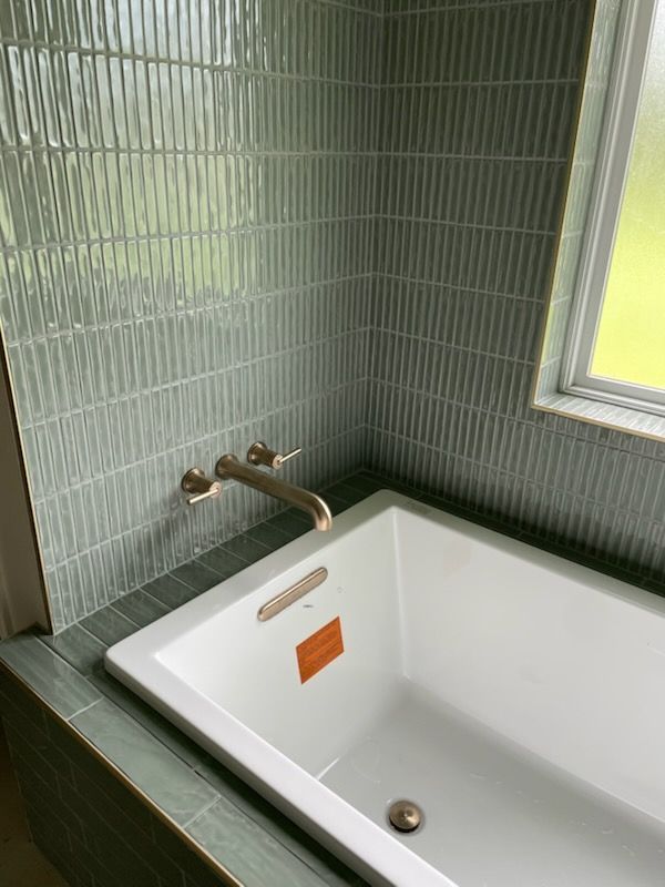 A rectangular bathtub in a bathroom with a window