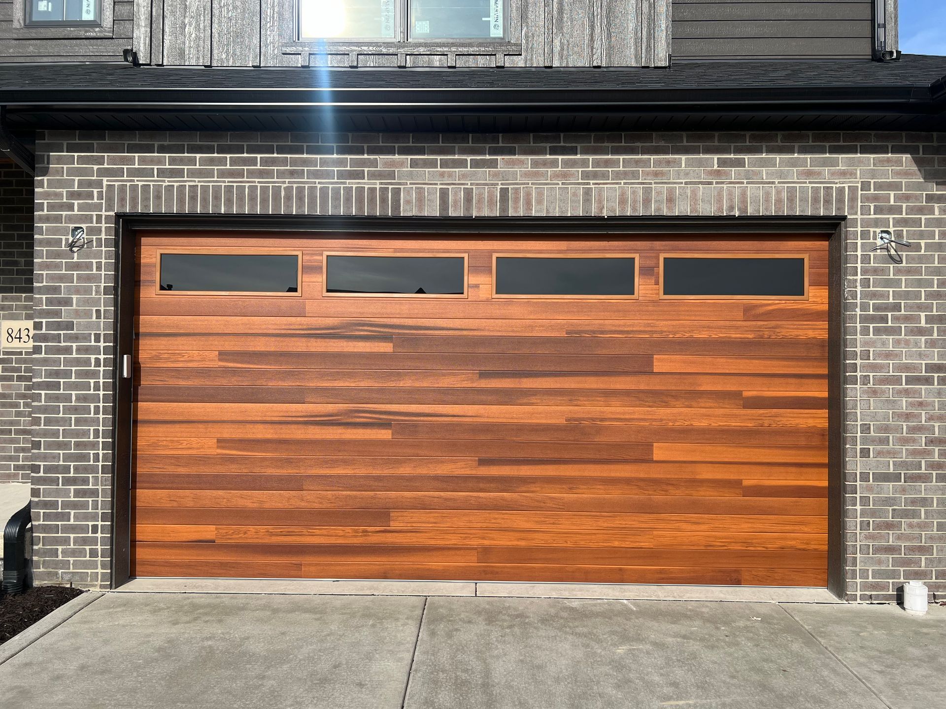 Wooden garage door with four small windows set in a brick house facade