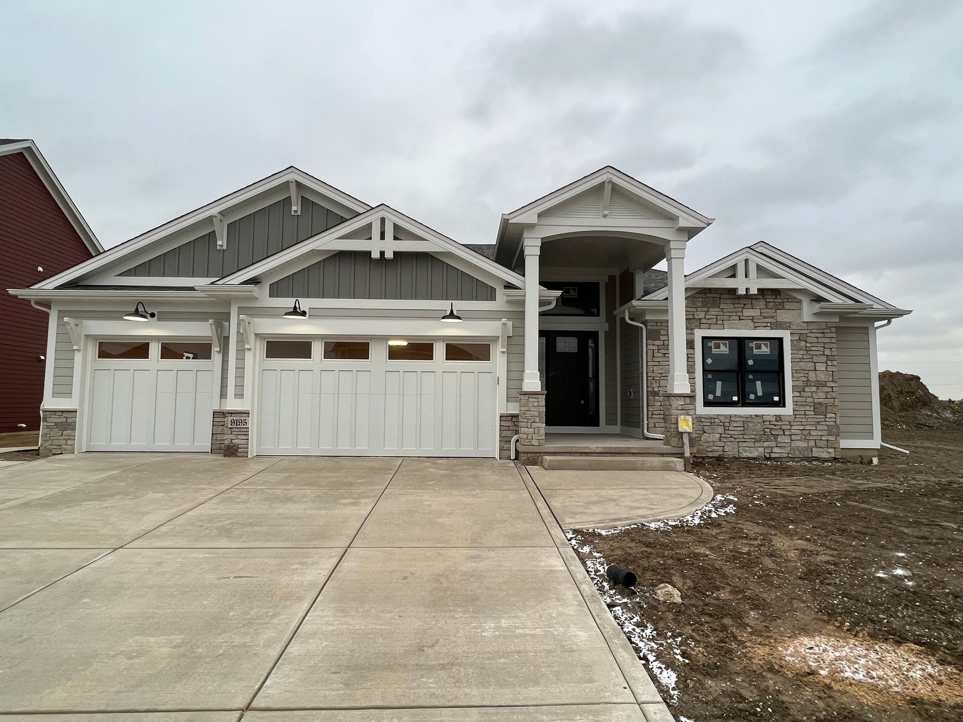 New single-story suburban house with a white garage and front porch under construction