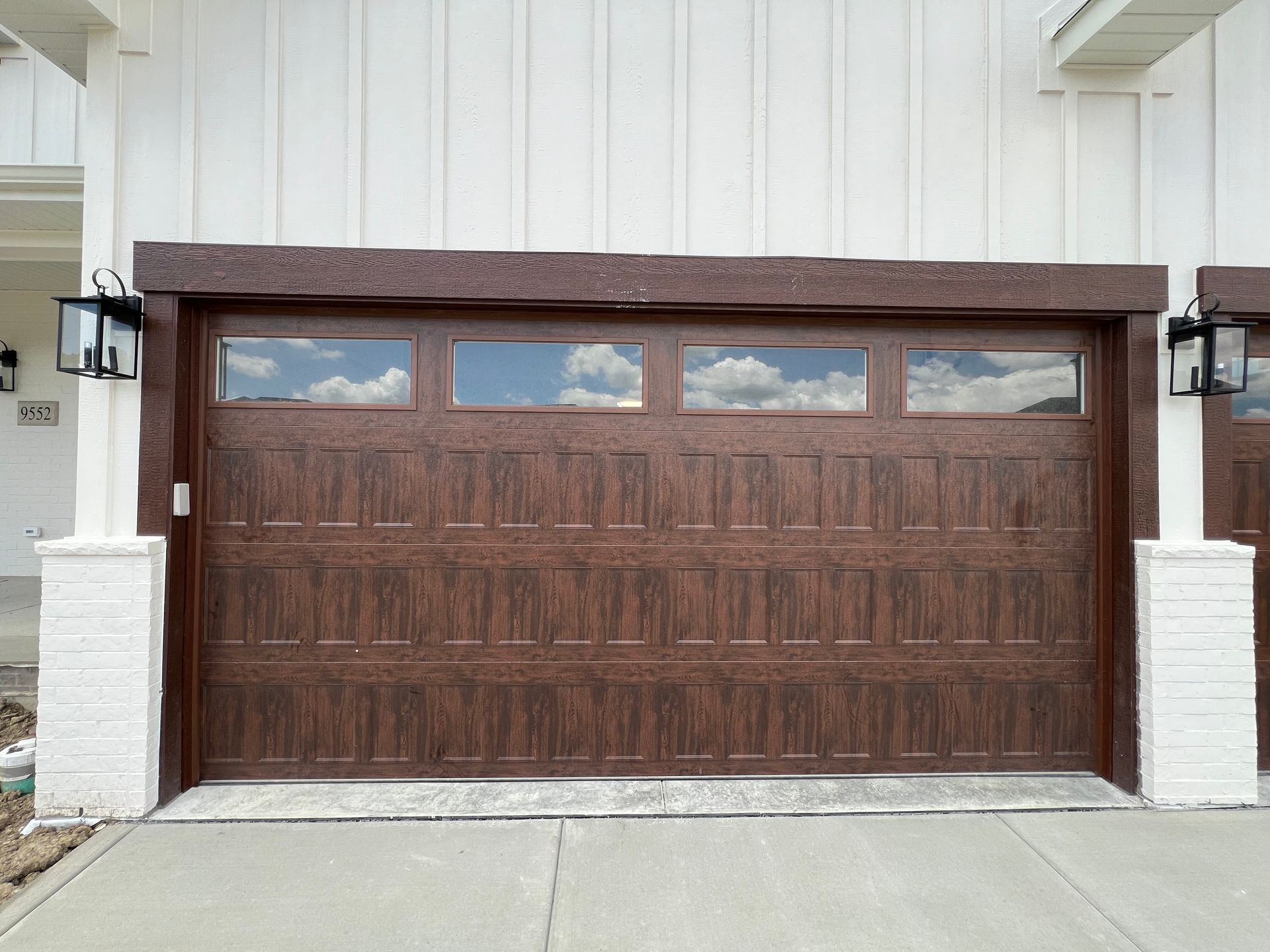 Wooden garage door with narrow windows, framed by white pillars on a house exterior