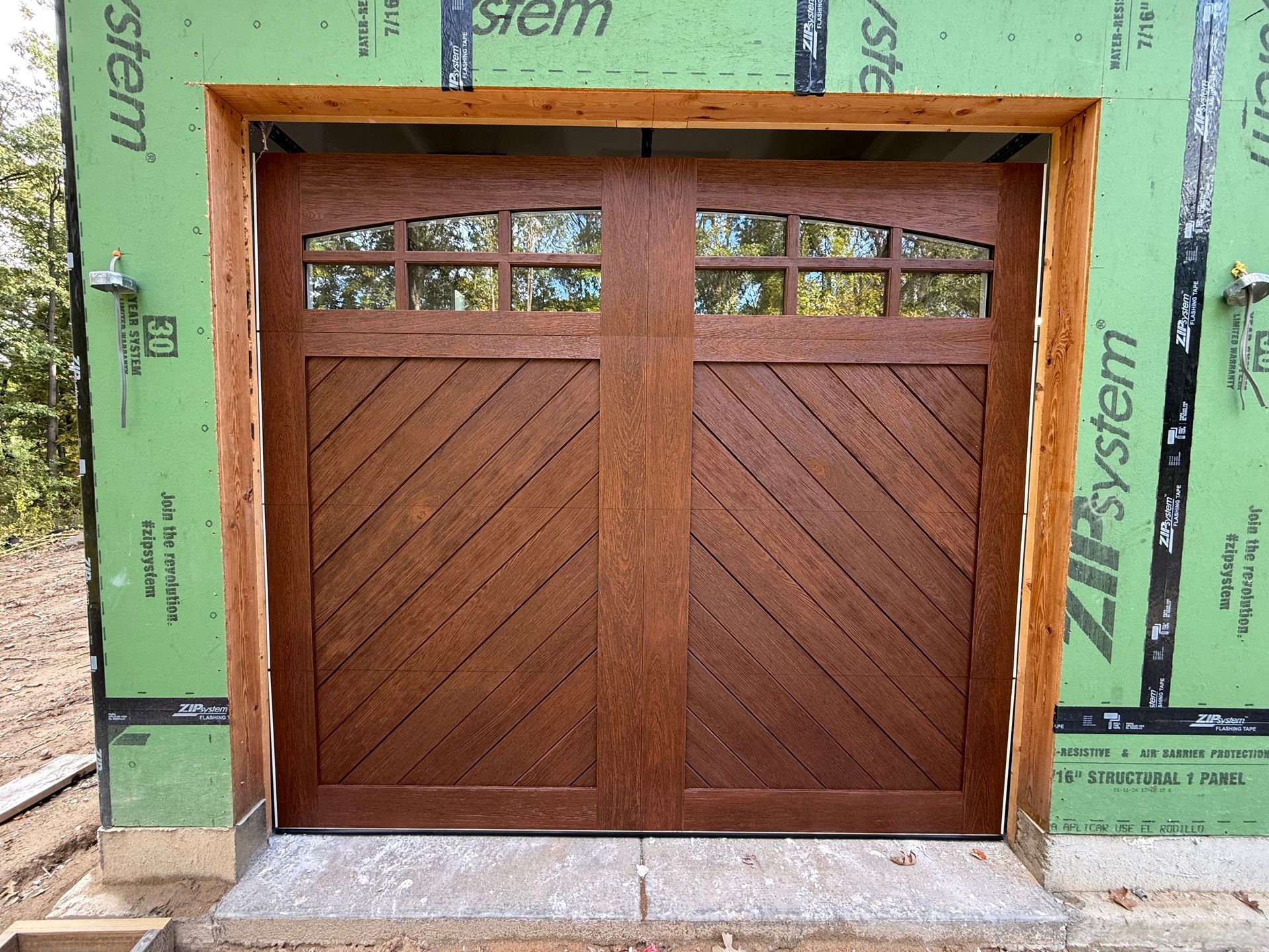 Wooden double garage door in a green construction frame
