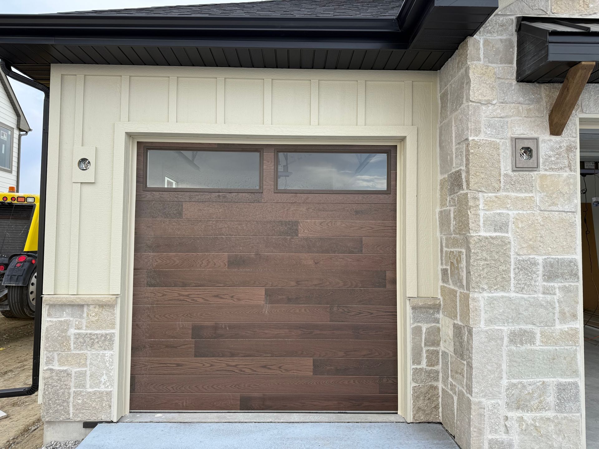 Wood-paneled garage door with frosted windows, set in a stone exterior facade