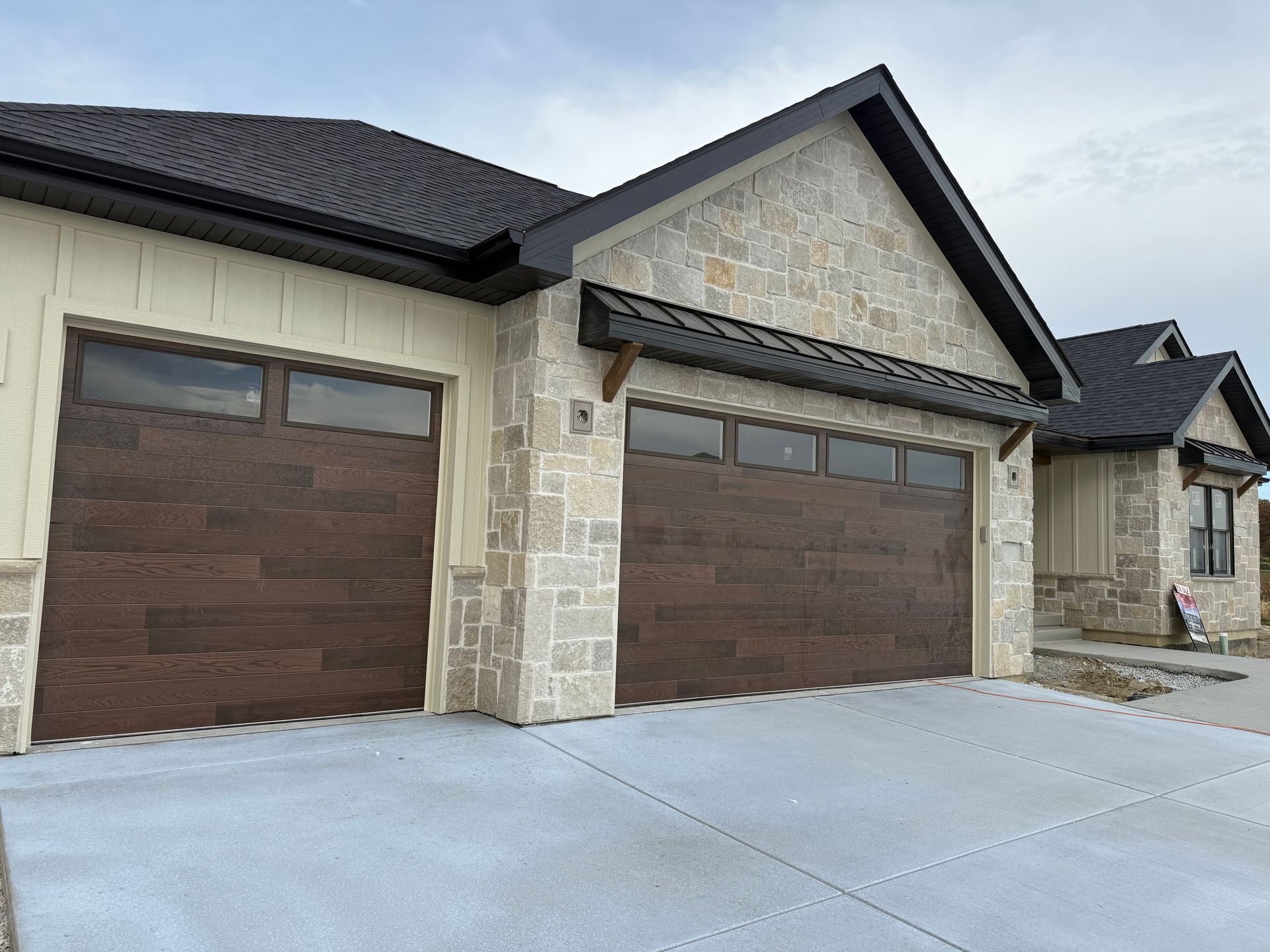 Modern brick house exterior with two wooden garage doors and a concrete driveway