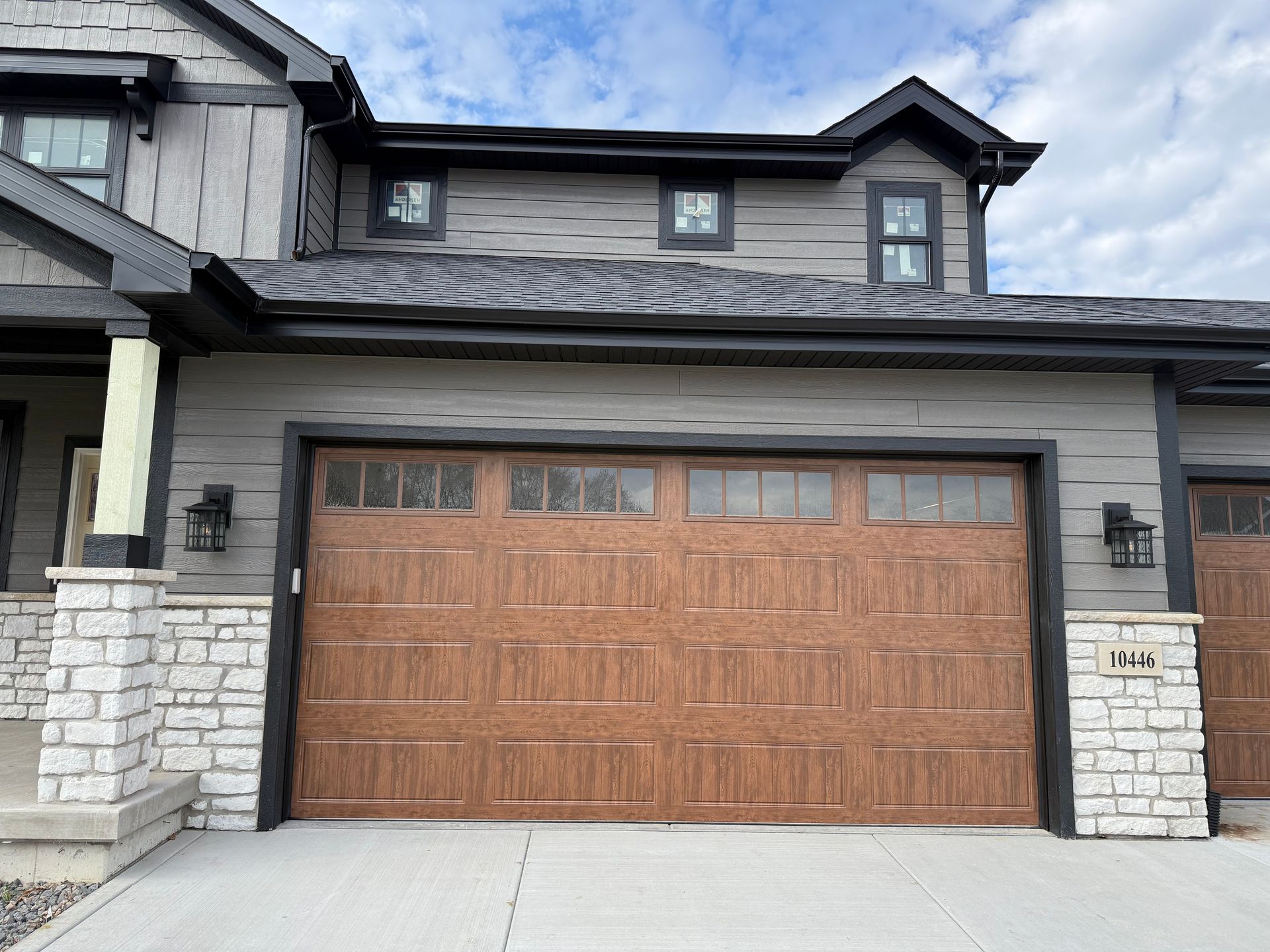 Modern house exterior with a wood double garage door and stone pillars