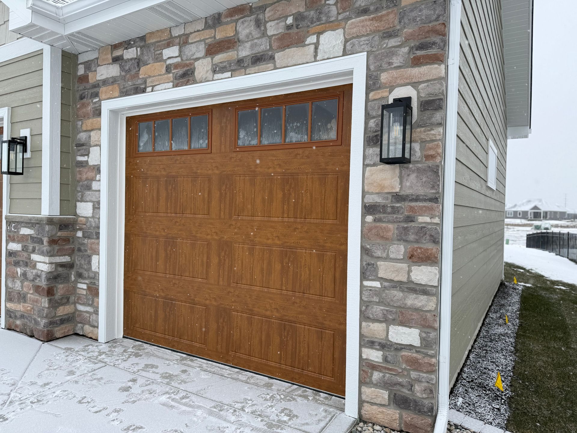 Snow-covered garage with a wooden door set in a stone exterior wall
