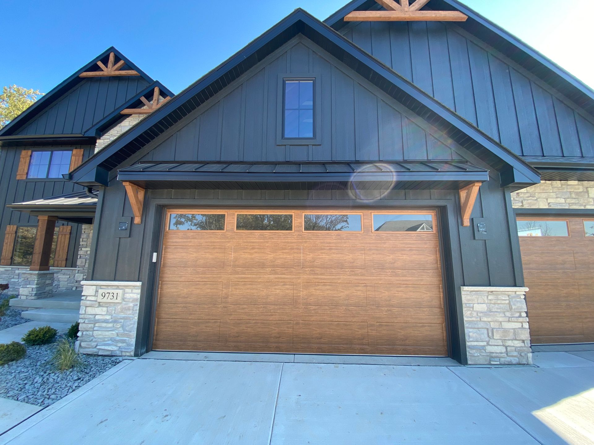 Modern house exterior with a two-car wooden garage door and stone accents