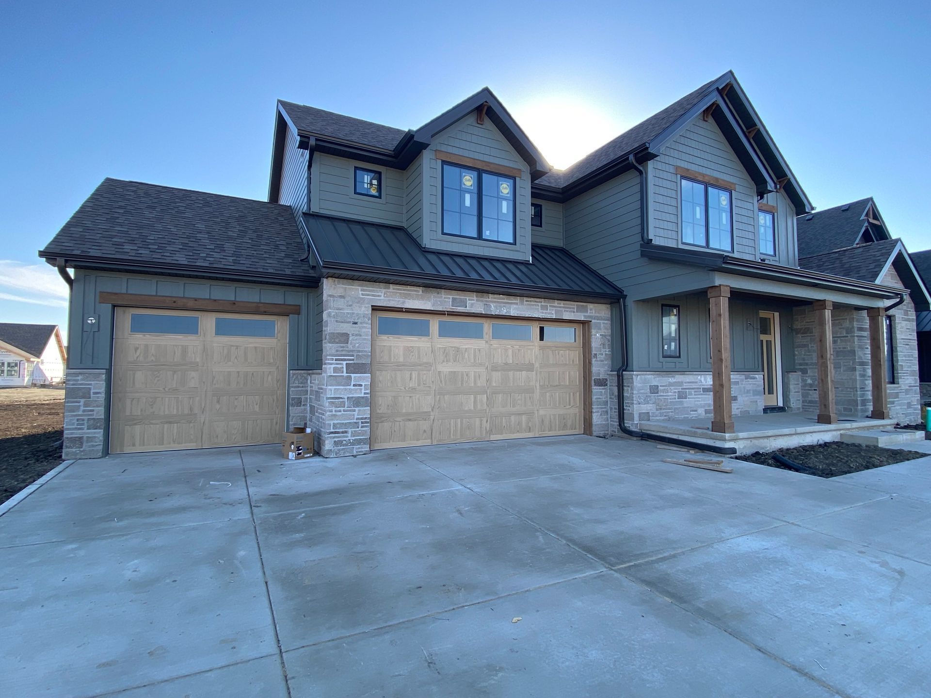 Large modern gray two-story house with a three-car garage and wide concrete driveway