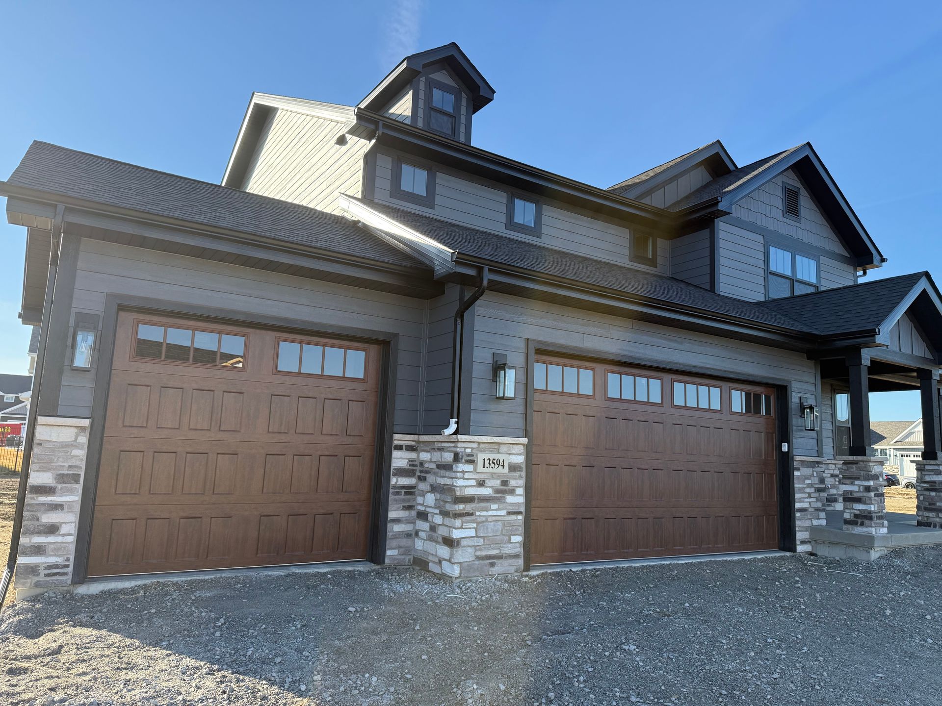 Two-car garage with brown doors and stone exterior on a large suburban house