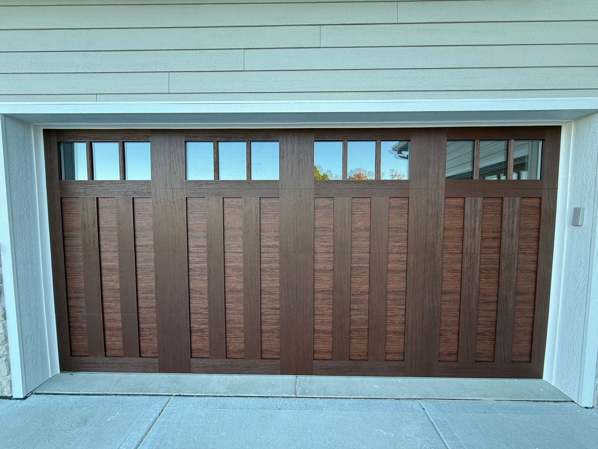 Brown wooden garage door with small windows under a light blue frame