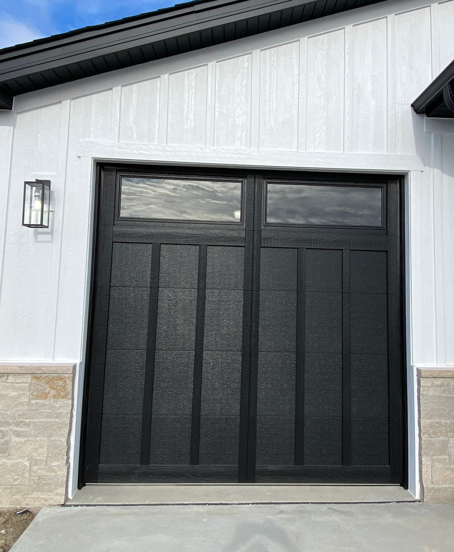 Black mesh garage door on a white building with stone trim