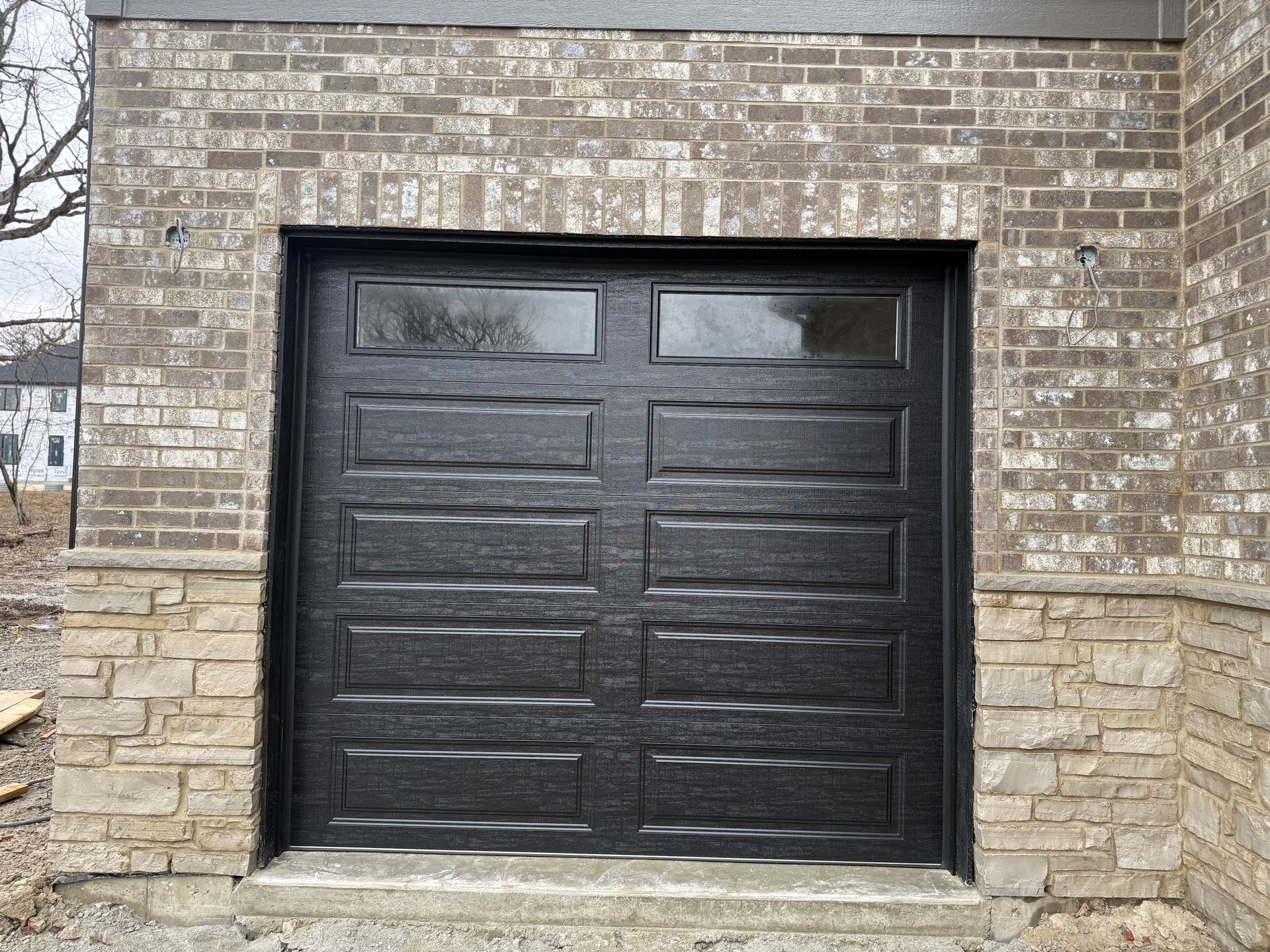 Black double garage door set in a brick house facade.