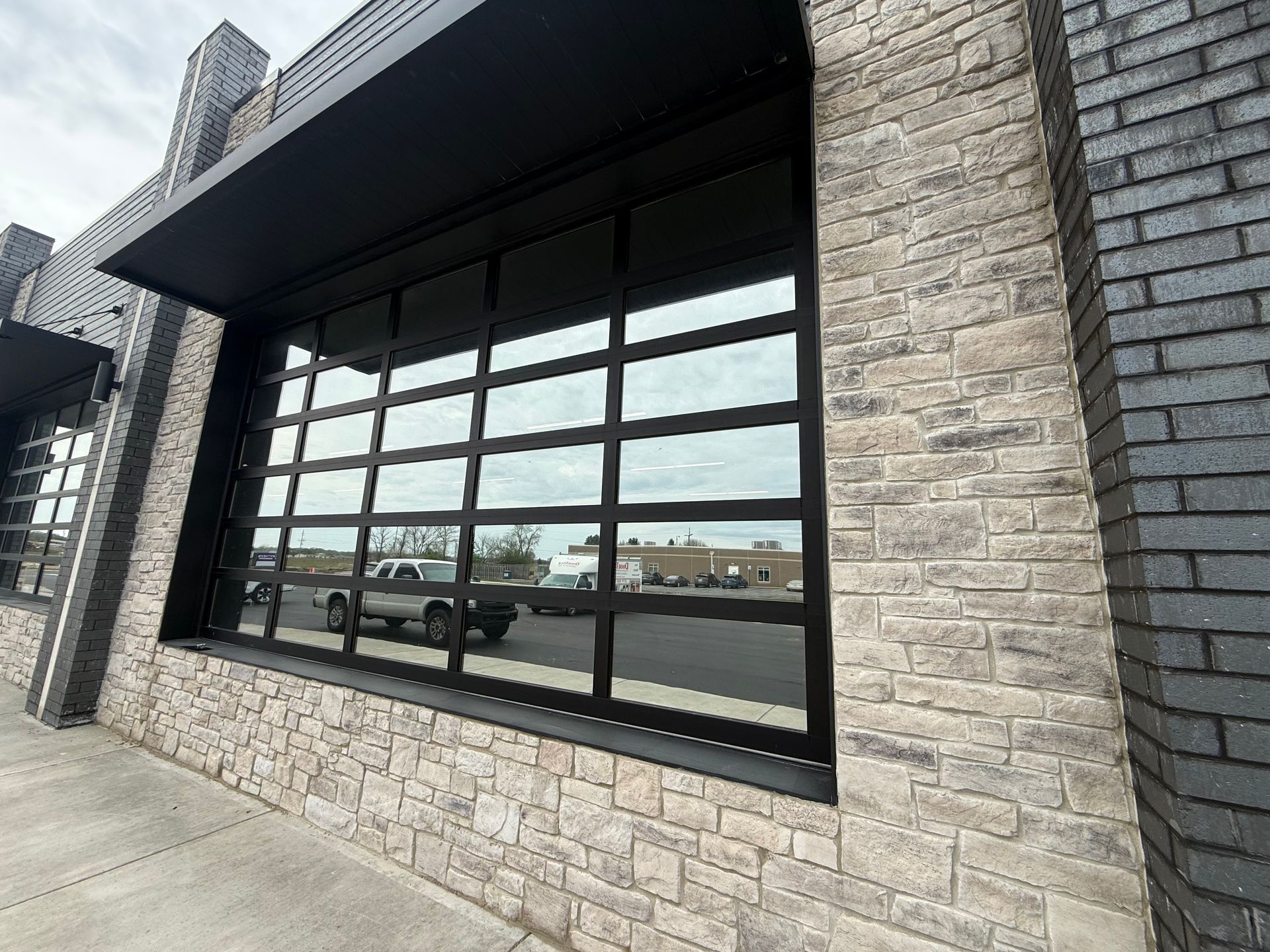Black-framed storefront windows set into a light stone facade on a modern building.
