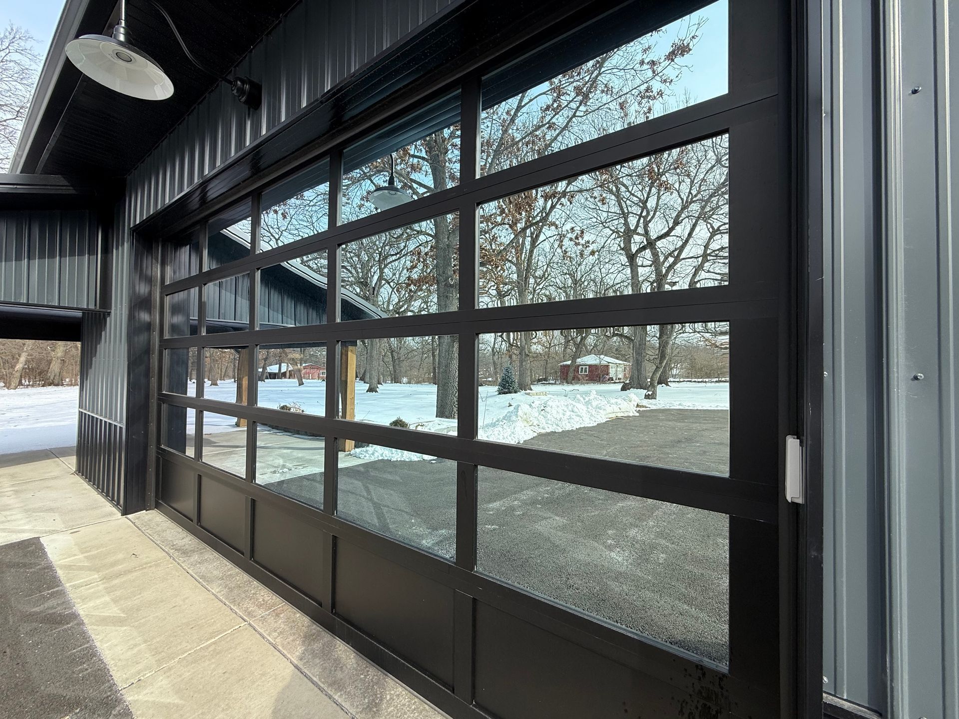 Glass storefront doors reflecting snow and trees outside a covered walkway