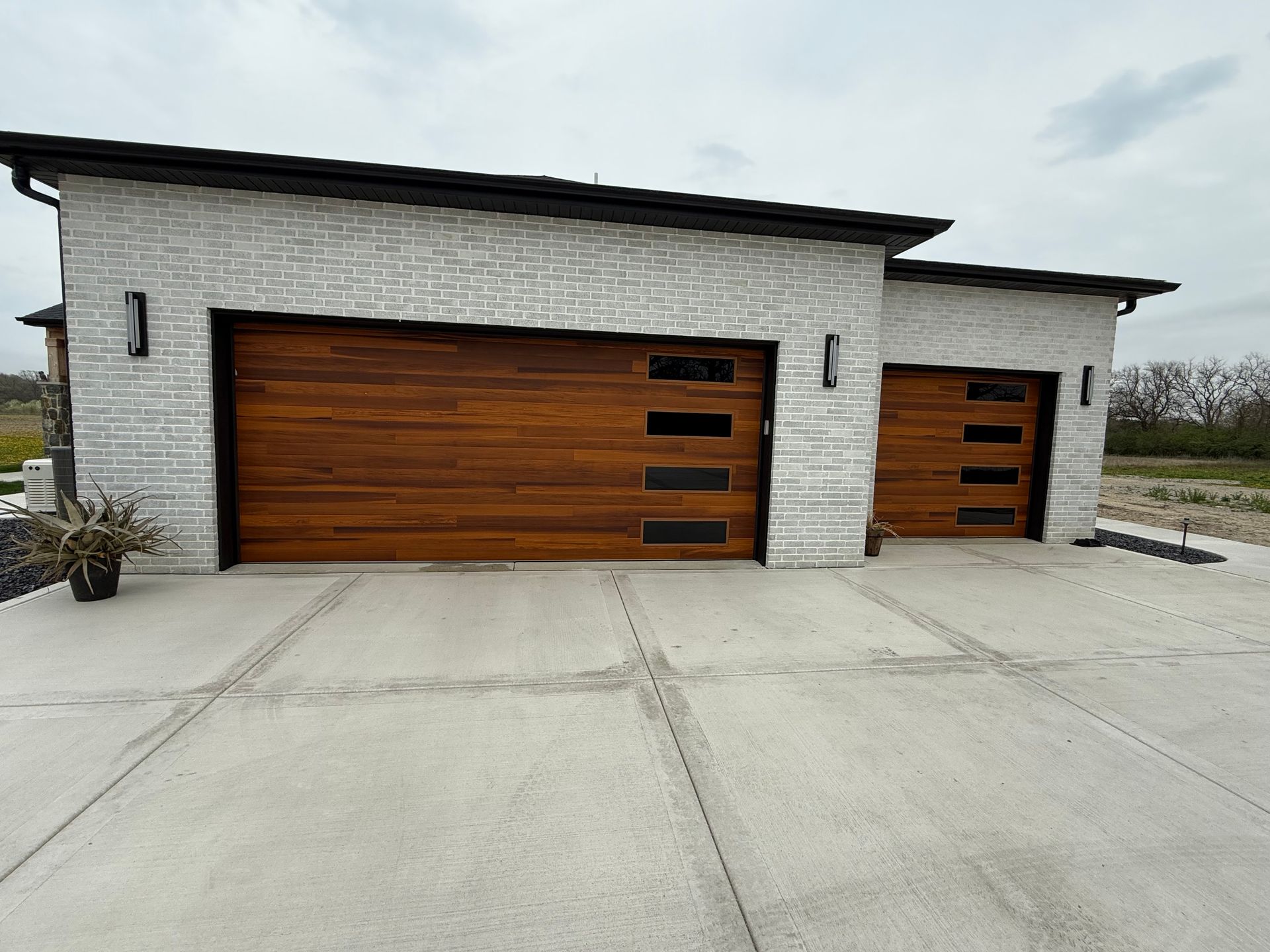 Modern white house exterior with two wood-paneled garage doors on a concrete driveway