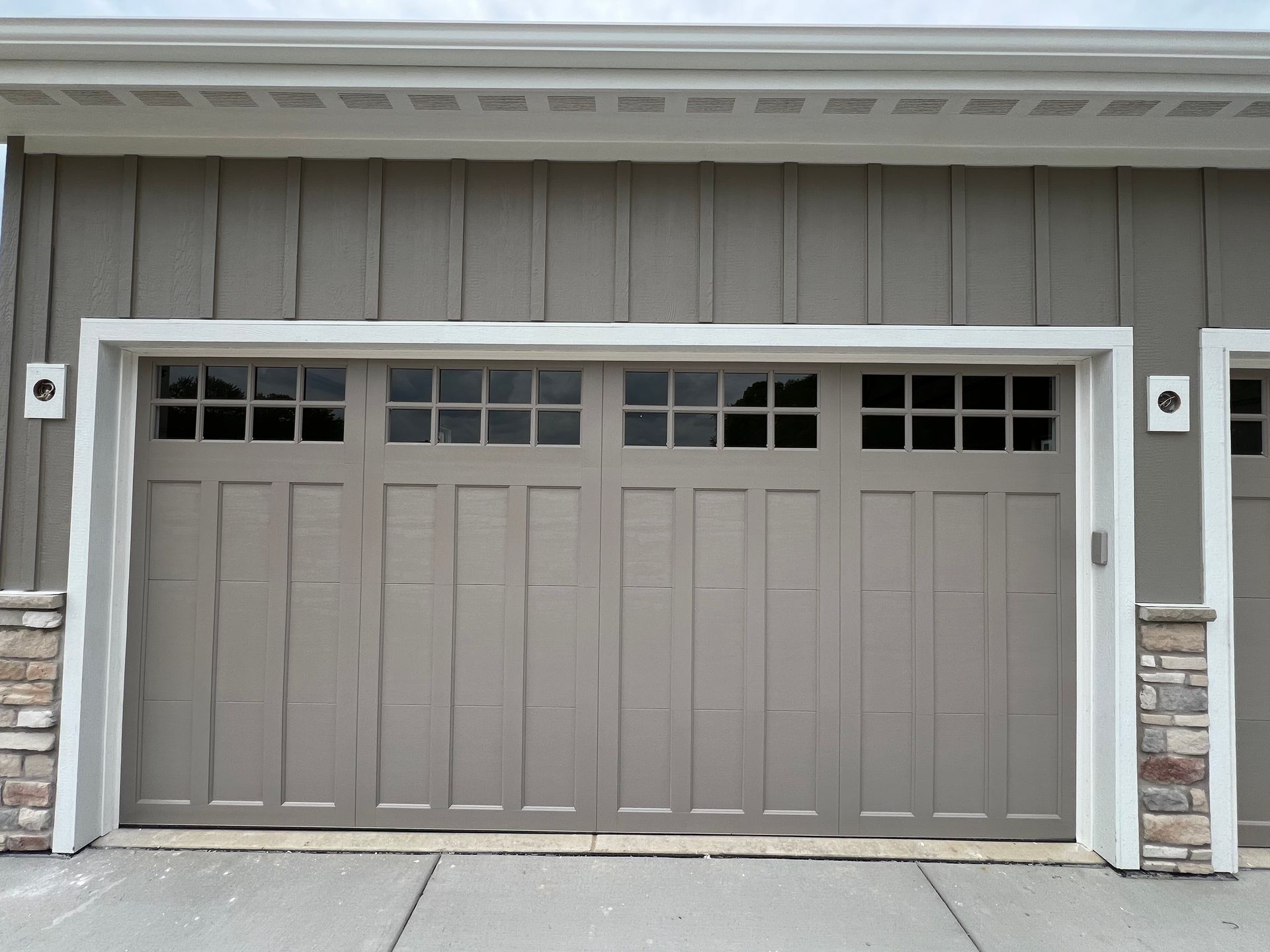 Gray two-car garage door with upper windows on a house exterior