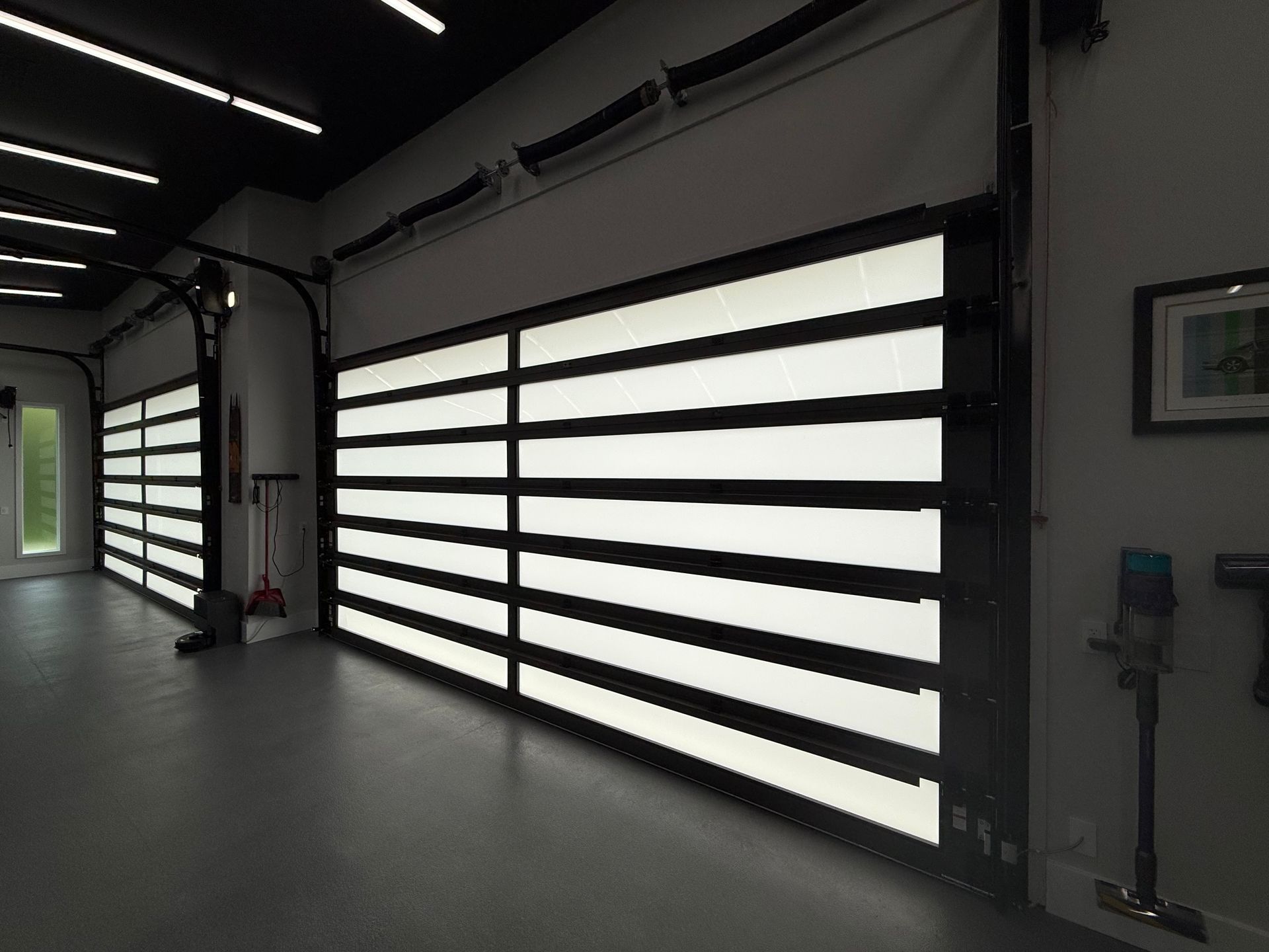 Modern garage interior with large frosted-glass roll-up doors and dark floor