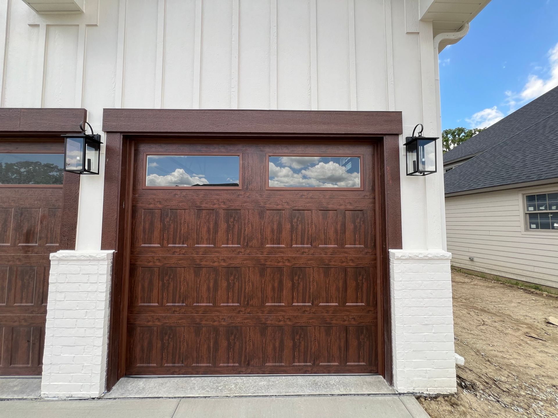 Brown garage door with small windows on a white house exterior