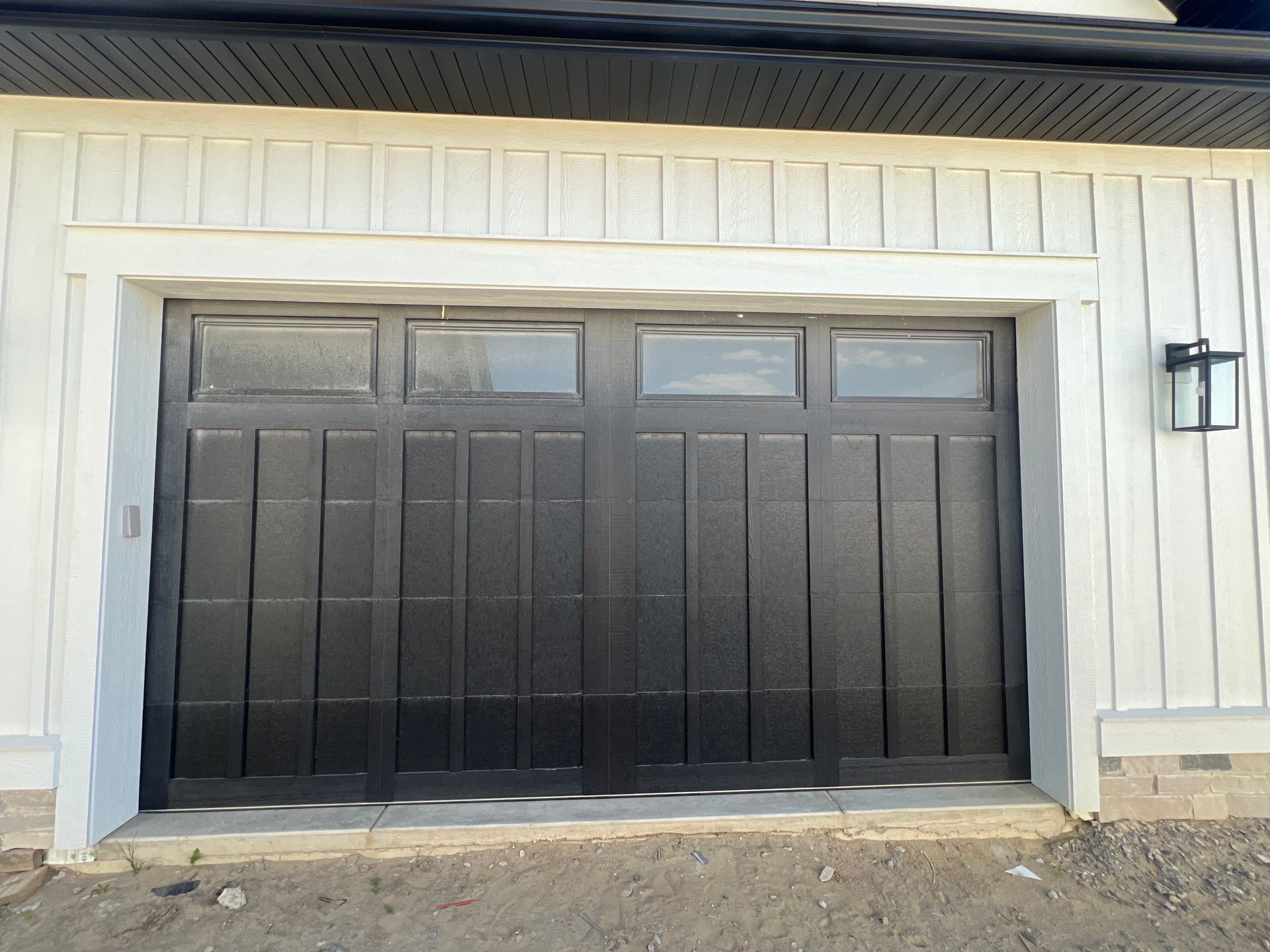 Black double garage door on a light-colored house exterior