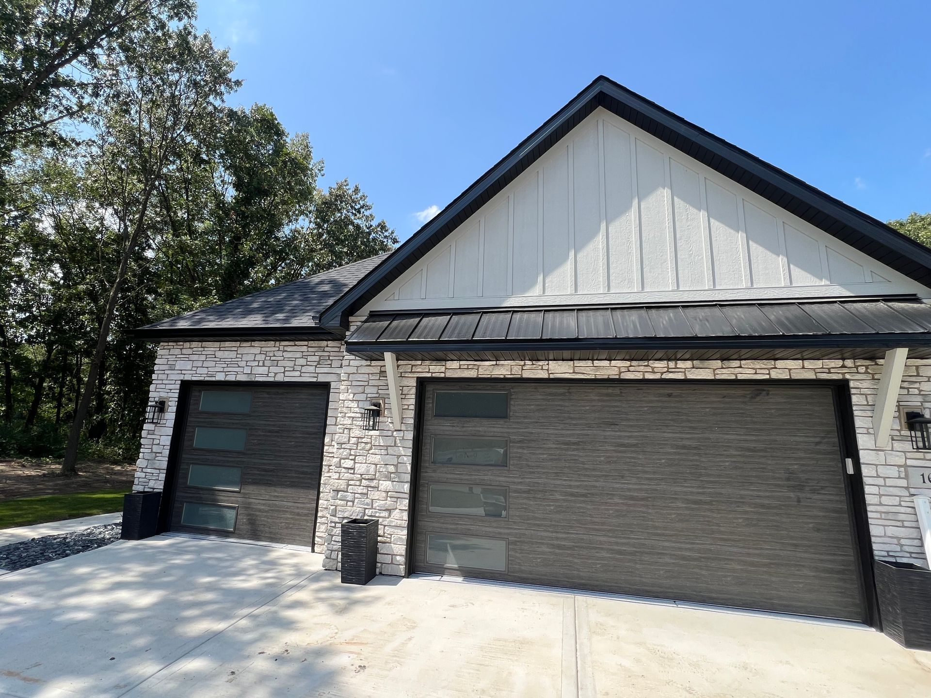 Brick house with two dark garage doors and a white gable, partly covered in snow