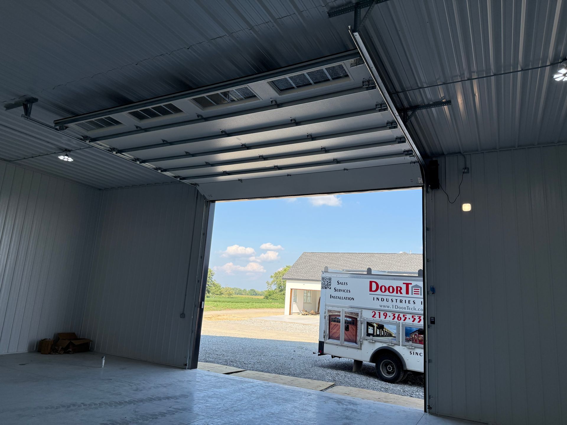 Open garage bay with a delivery truck parked outside in bright daylight