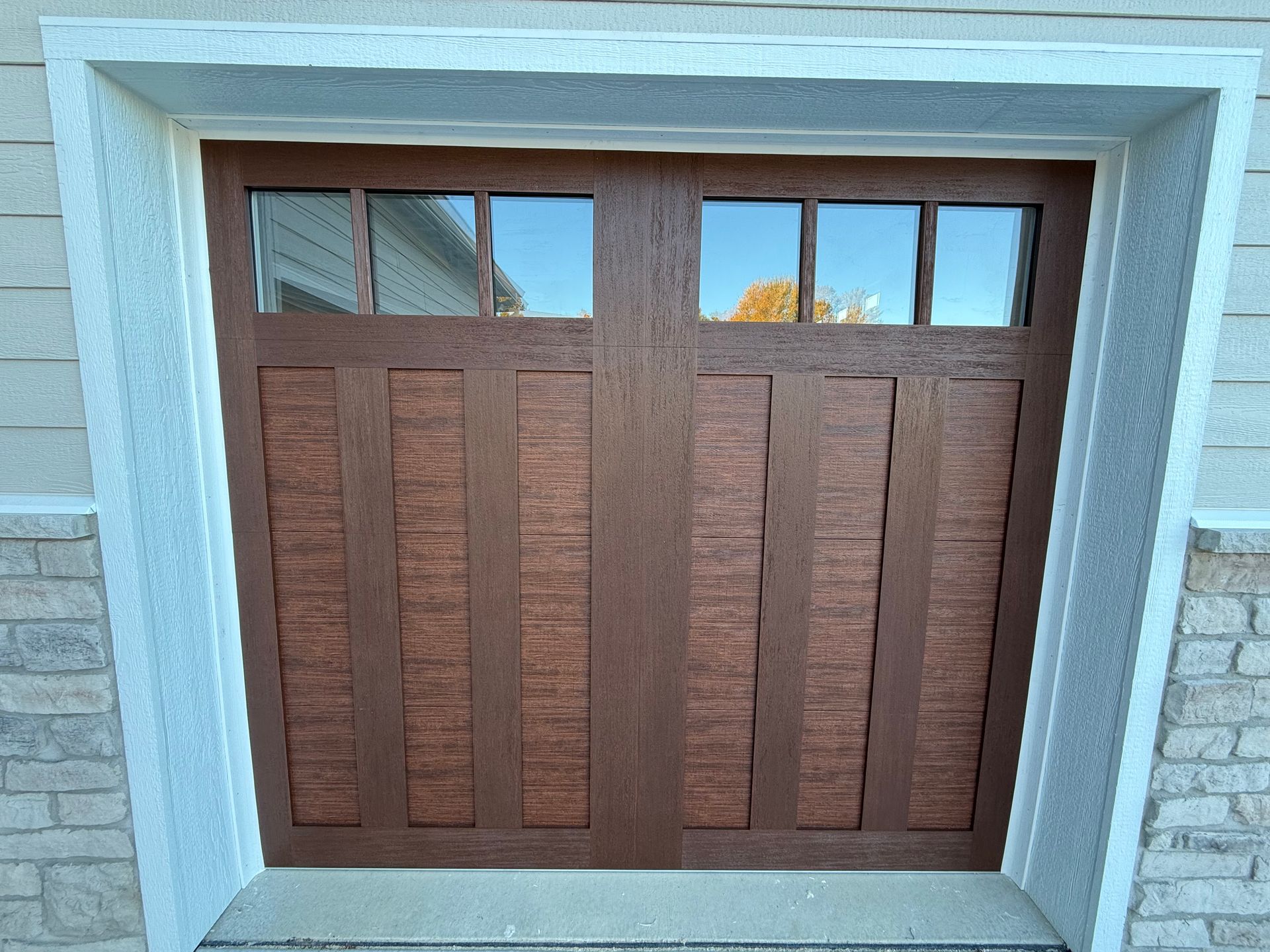 Wooden front door with two panels, set in a light gray stone frame.