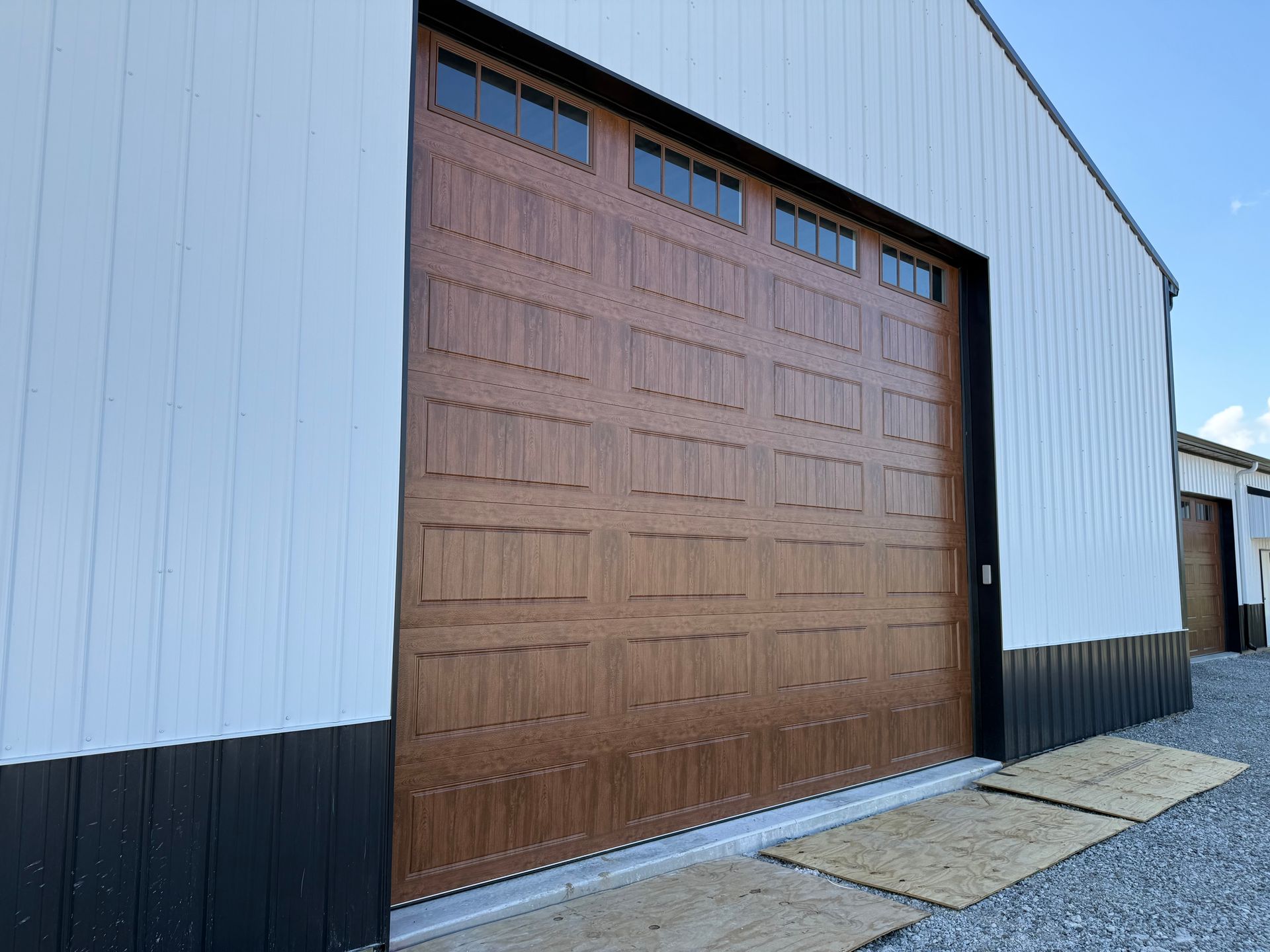 Large brown warehouse door on a white-and-black industrial building with concrete pavement in front