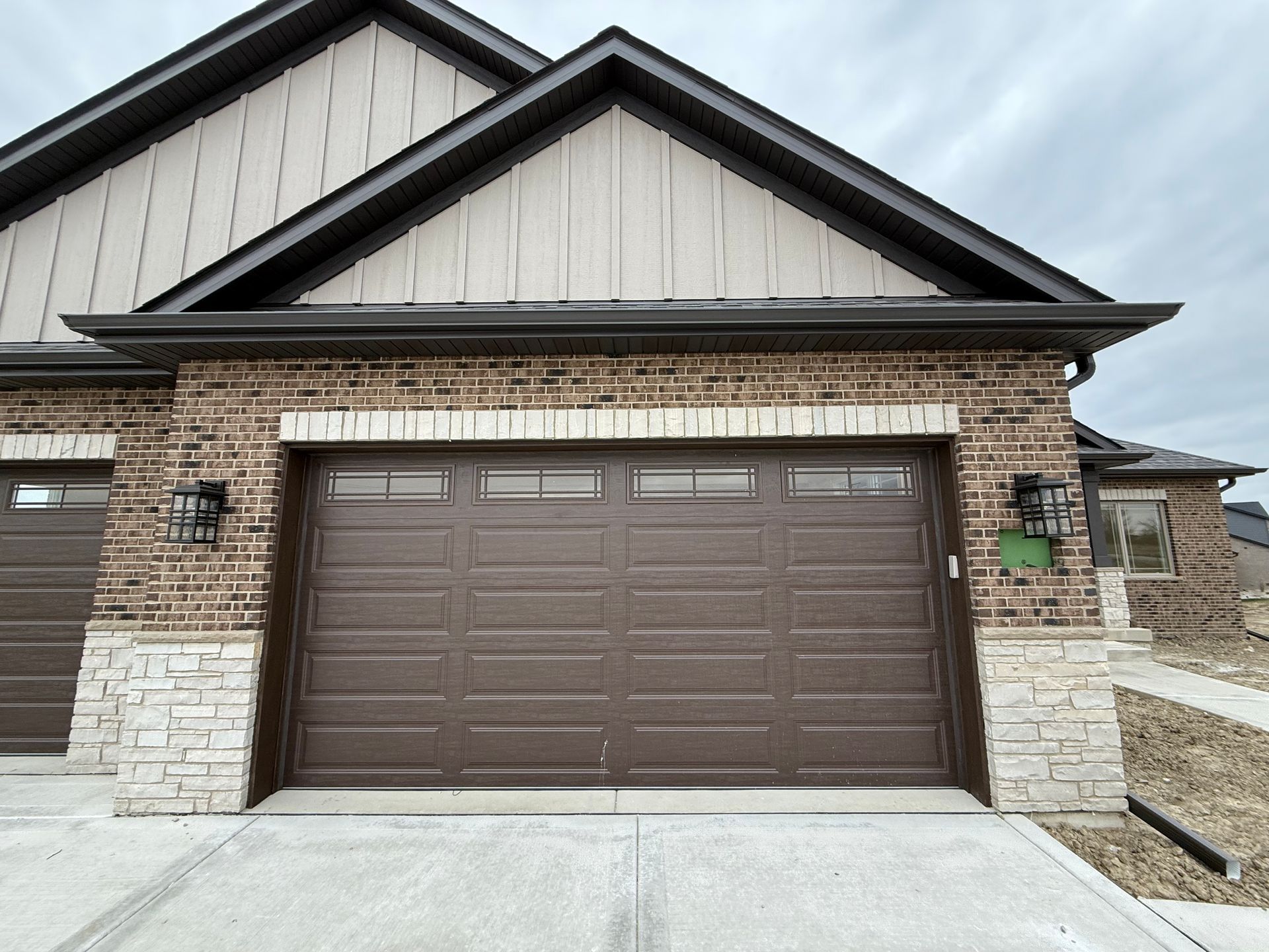 Front view of a house with brown garage door, brick siding, and a concrete driveway