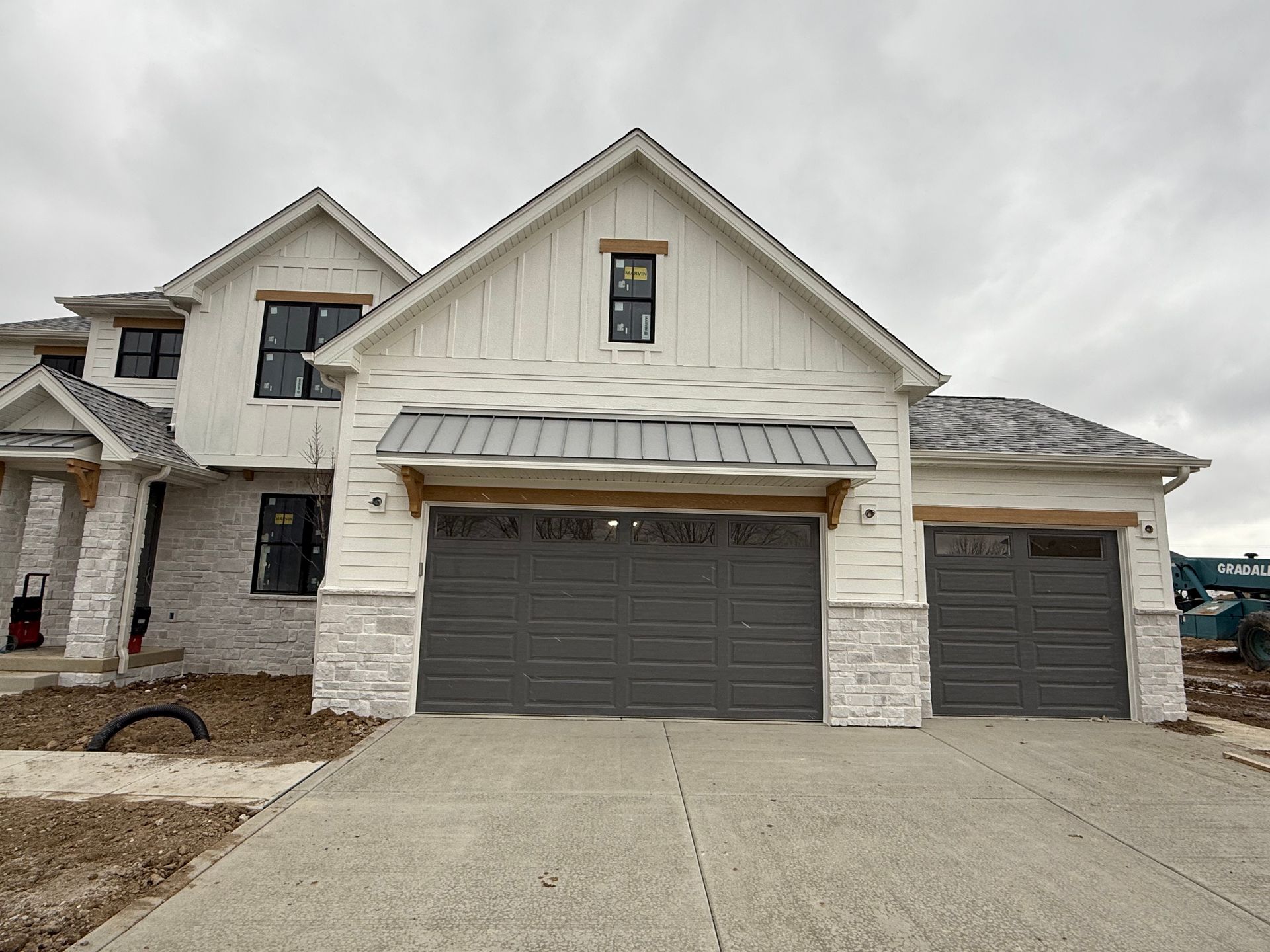Suburban house exterior with three garages, white siding, stone accents, and a concrete driveway