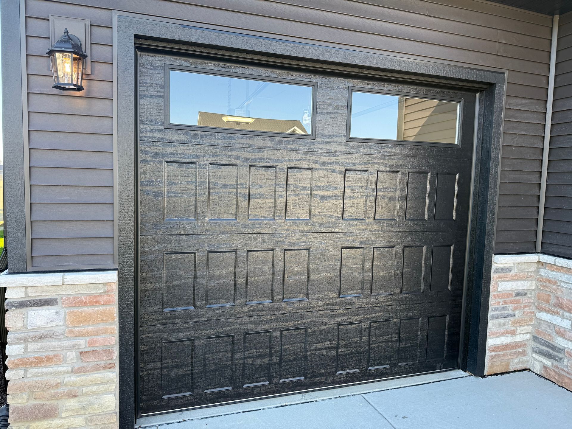 Black garage door with small windows on a house exterior