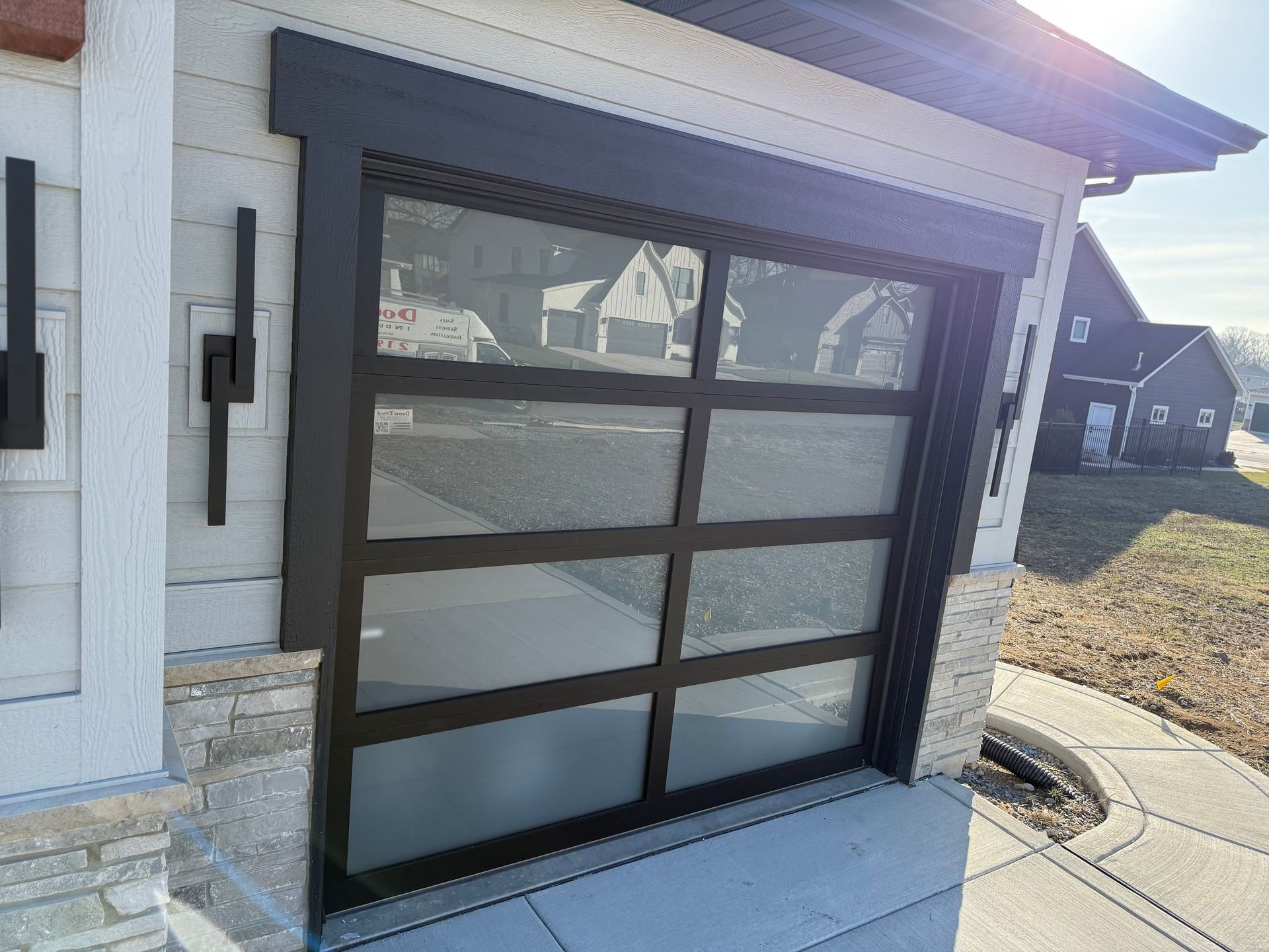 Black garage door with frosted glass panels on a modern home exterior