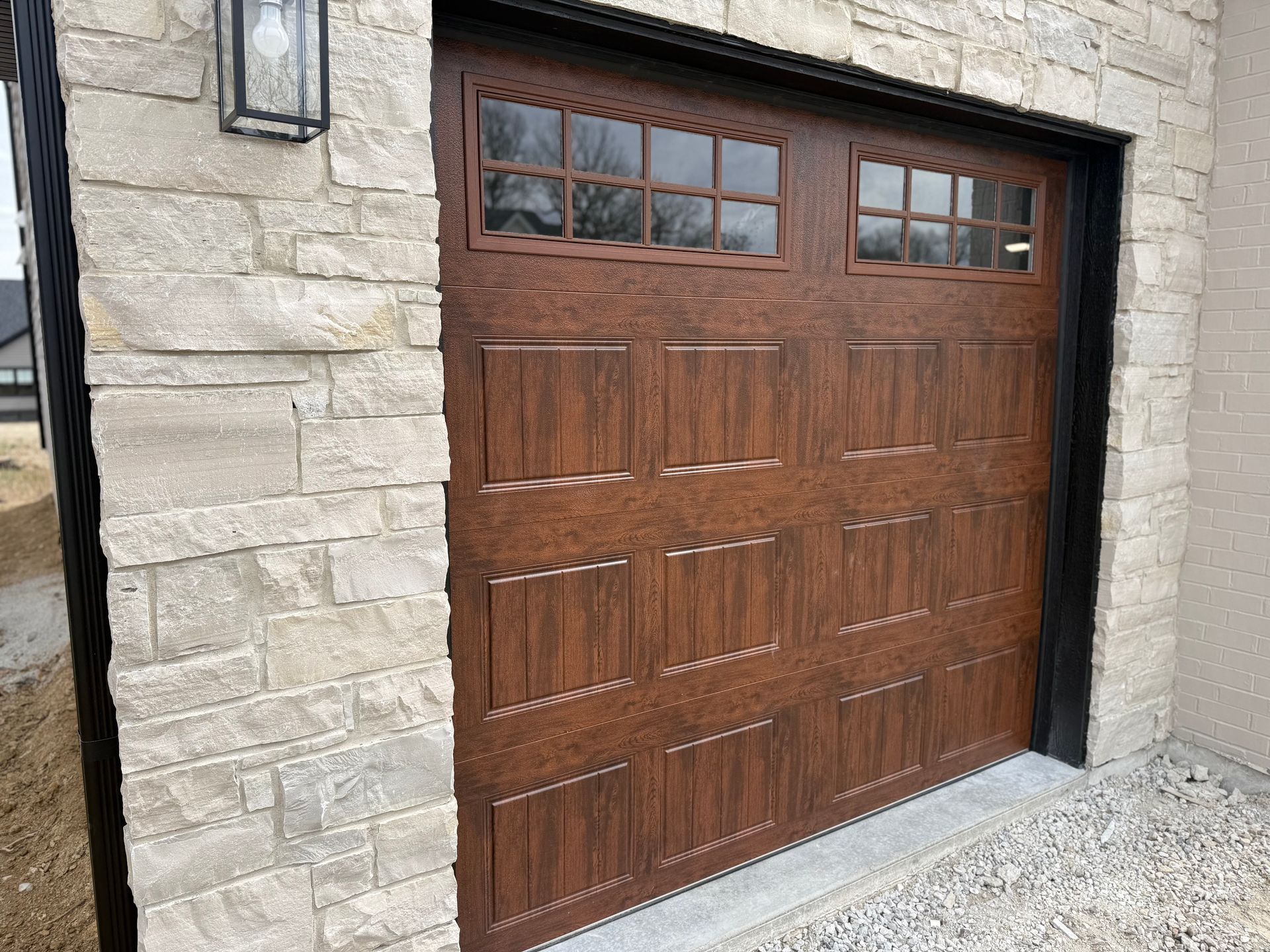 Brown wooden garage door set in a stone exterior wall with small windows along the top.