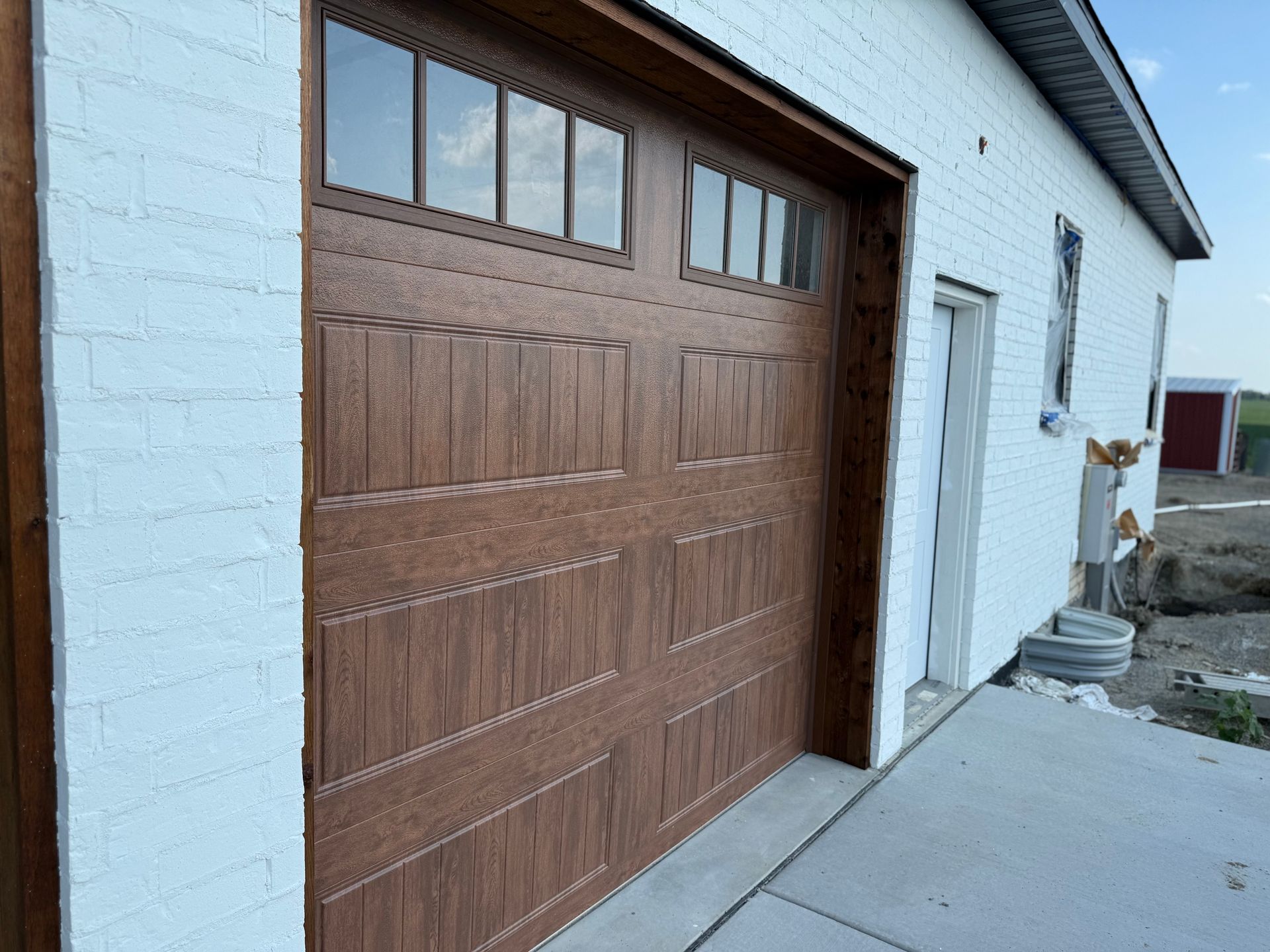 Brown garage door on a white brick building with a concrete driveway