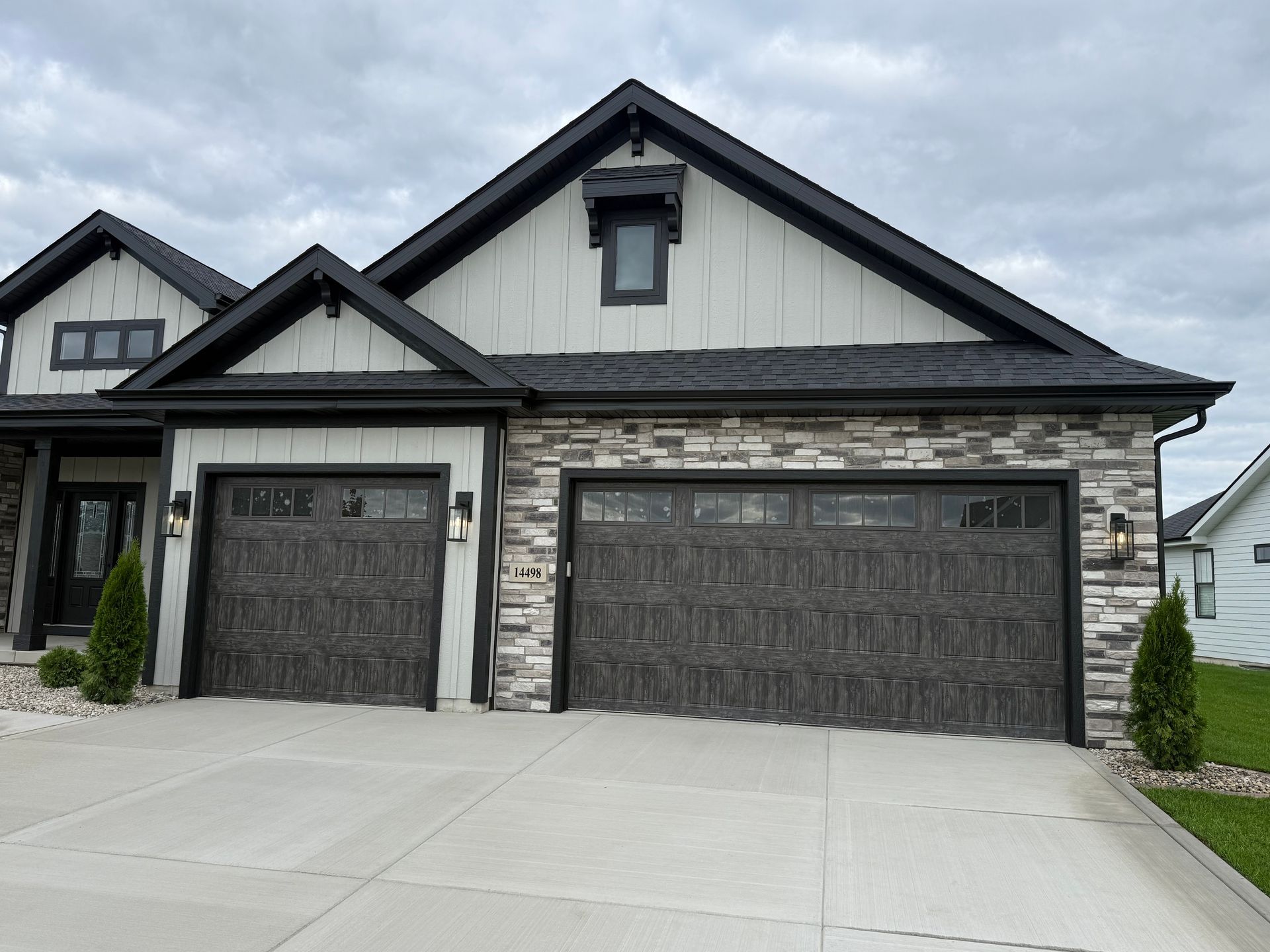 Modern suburban house exterior with two dark garage doors and a wide concrete driveway