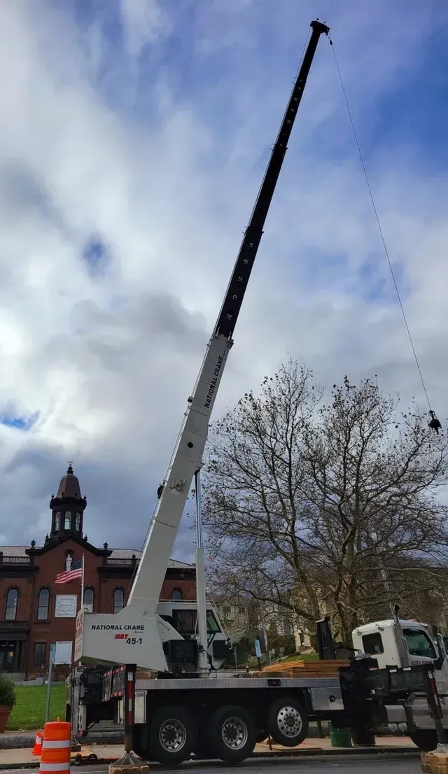 Crane lifting something; building in background under cloudy sky.