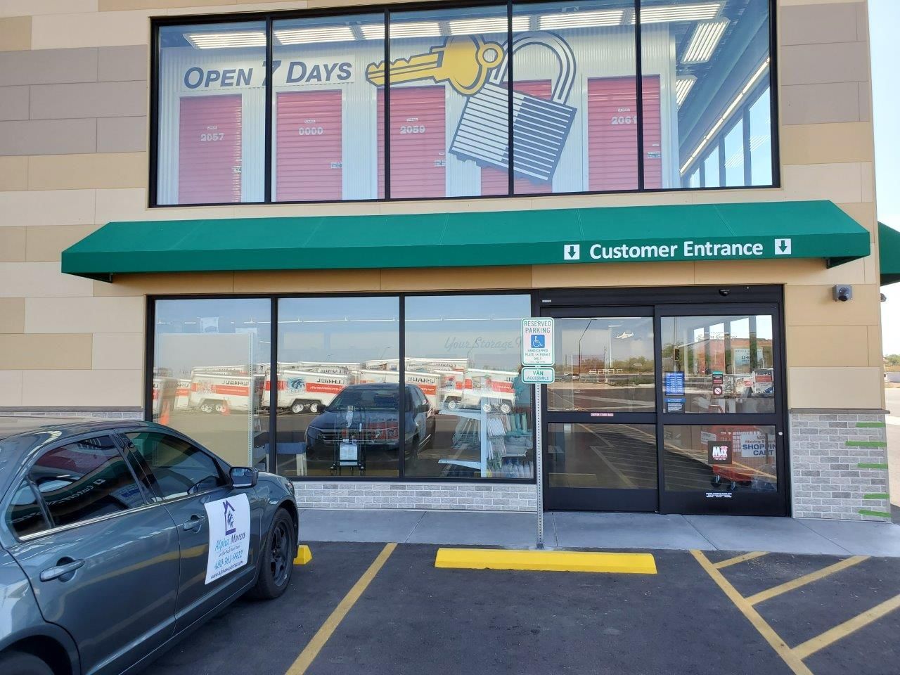 A car is parked in front of a store with a green awning.