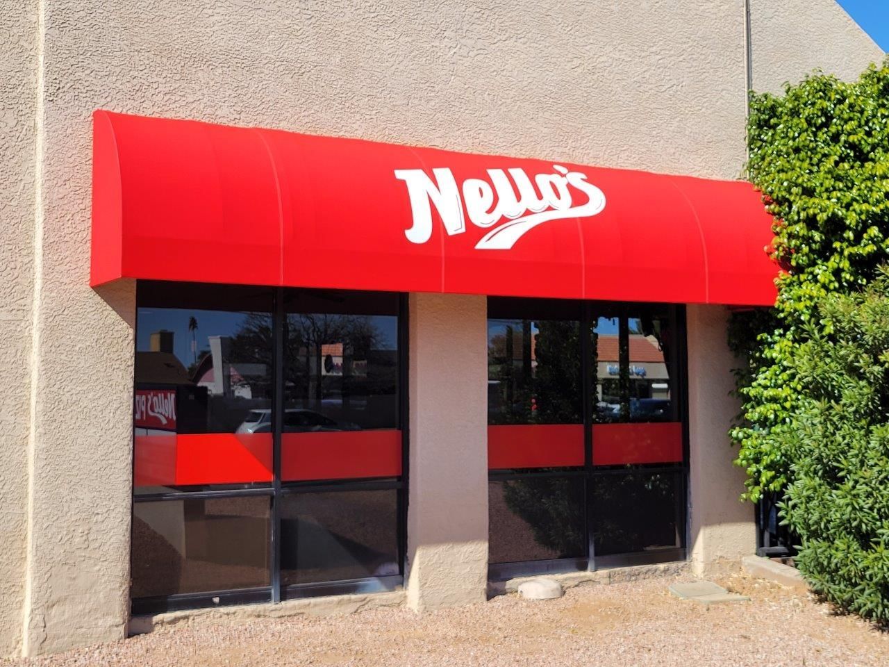 A building with a red awning that says Nello's ' on it