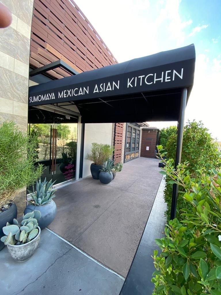 A person is taking a picture of the entrance to the mexican asian kitchen restaurant.