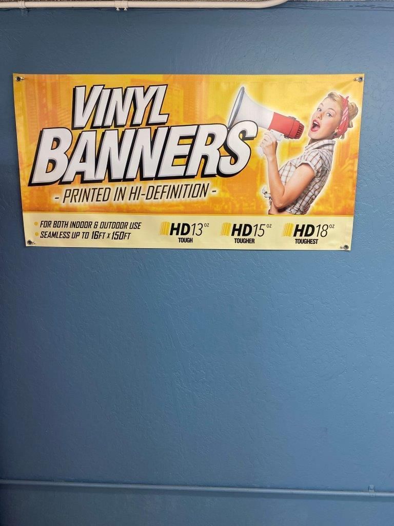 A vinyl banner with a woman holding a megaphone is hanging on a wall.