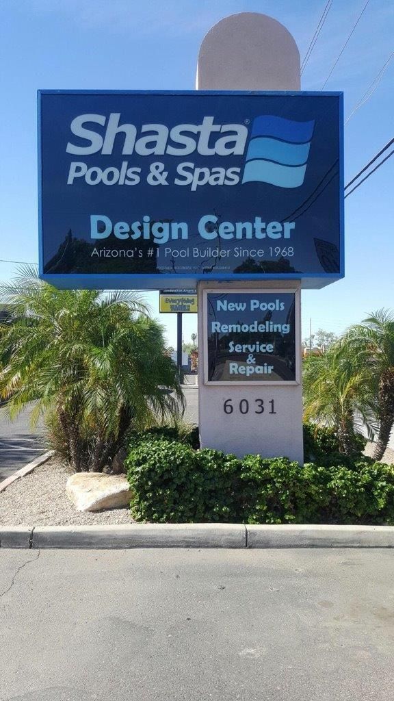 A sign for shasta pools and spas design center is sitting on the side of the road.