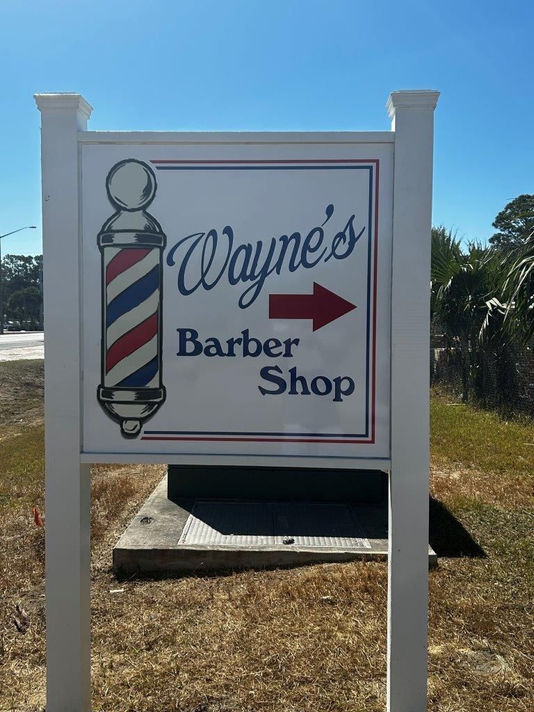 A sign for wayne 's barber shop with an arrow pointing to the right