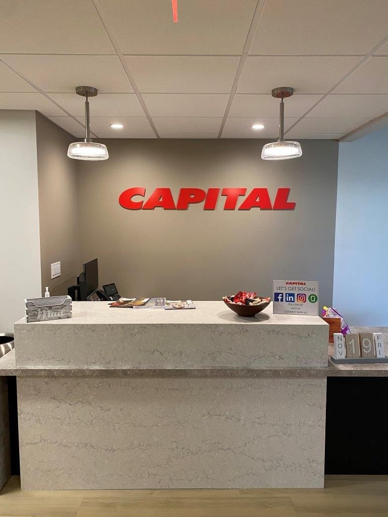 A white counter with a red capital sign on the wall.