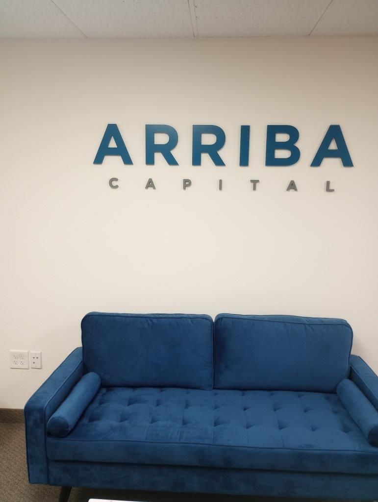 A blue couch under a sign that says arriba capital