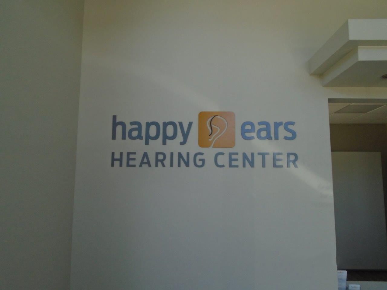A sign on a wall that says happy ears hearing center